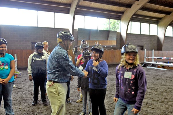 Southampton Intermediate School Principal Timothy Frazier gets a riding lesson from the girls at their graduation from the program on Monday at Wollfer Stables in Sagaponack. DANA SHAW