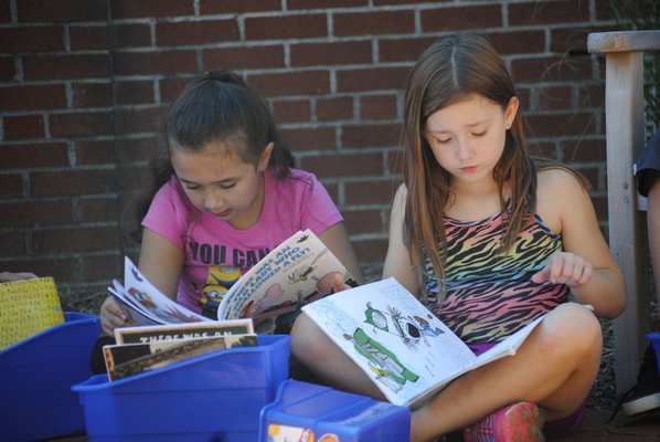 Kayden Mulvaney, left, and Skyler Daugherty read their books in the East Quogue reading garden. AMANDA BERNOCCO