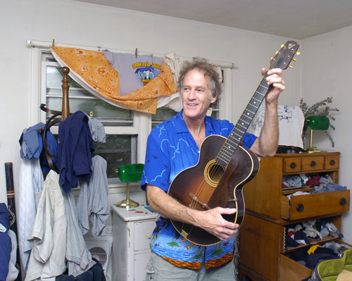 Jim Turner playing his vintage Martin accoustic guitar in his slightly messy room.