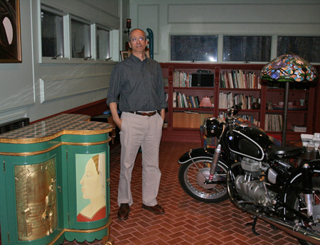 Manorville artist Joe Fratello with a Renaissance art-inspired cabinet he made and a motorcycle he restored. JESSICA DINAPOLI