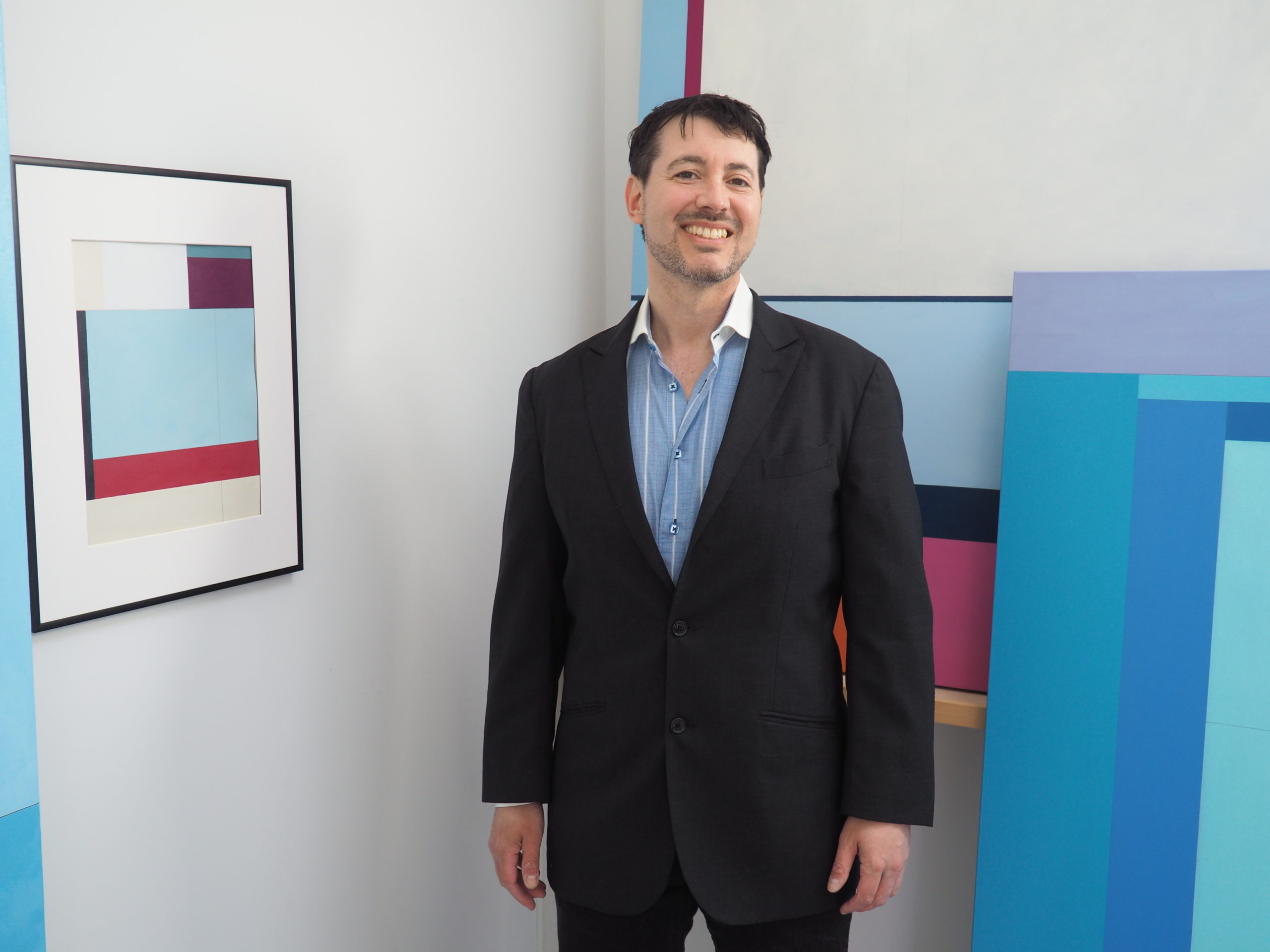 Chris Kelly in his studio surrounded by his paintings.