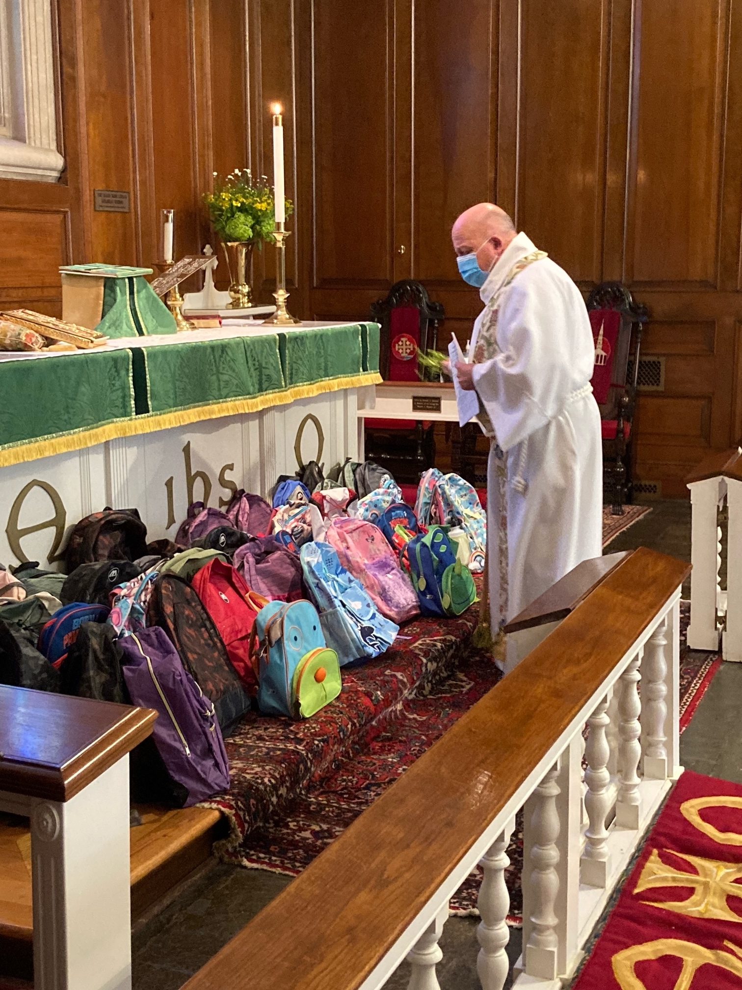 St. Mark’s Episcopal Church Rector Father Chris Jubinski blesses backpacks church parishioners in Westhampton gathered and donated — filled with school supplies — to give to children in need this fall.