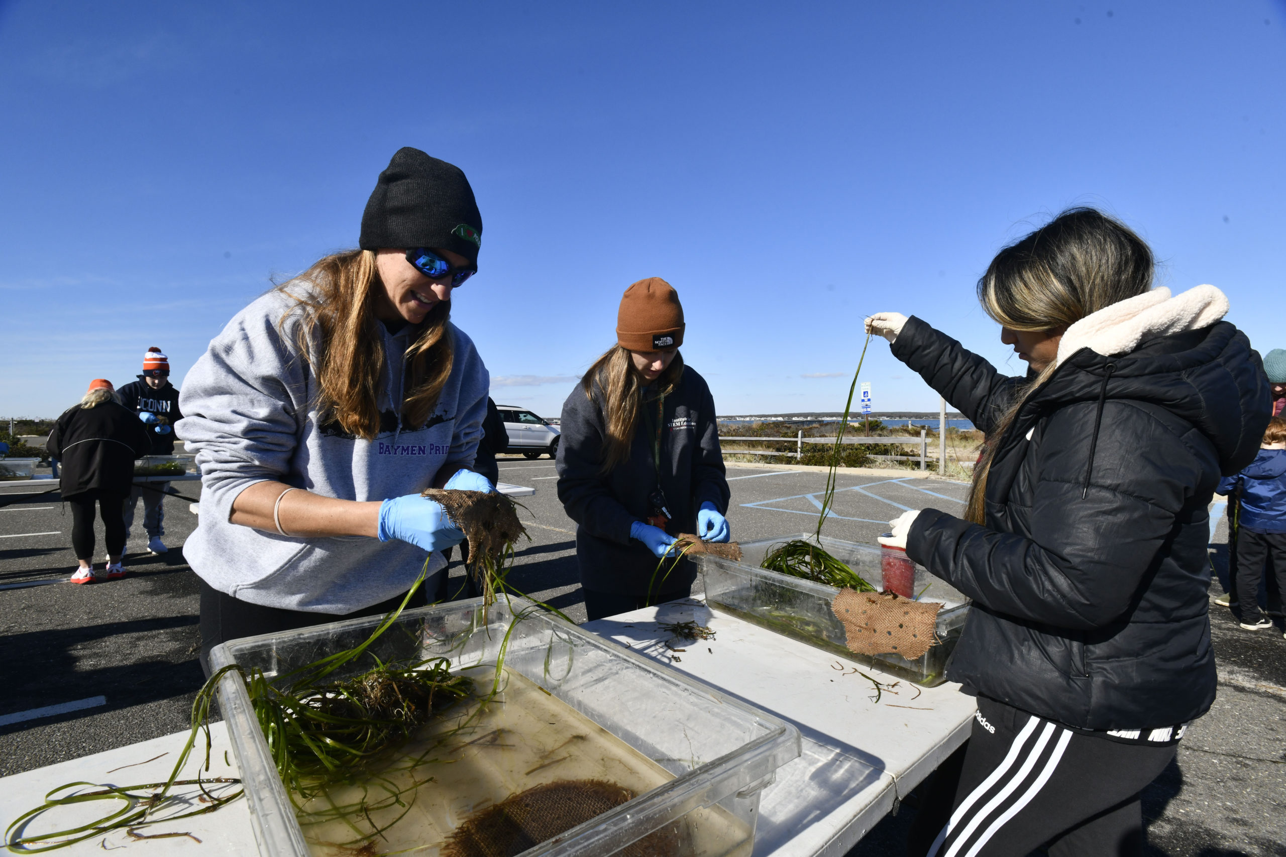 Hampton Bays High School science teachers Heather Turnbull and Brittany Castoro and student Janelle Rodas weave eelgrass at the Cornell Cooperative Extension's Marine Meadows Workshop at the Tiana Bayside Facility in Hampton Bays on Saturday.  DANA SHAW