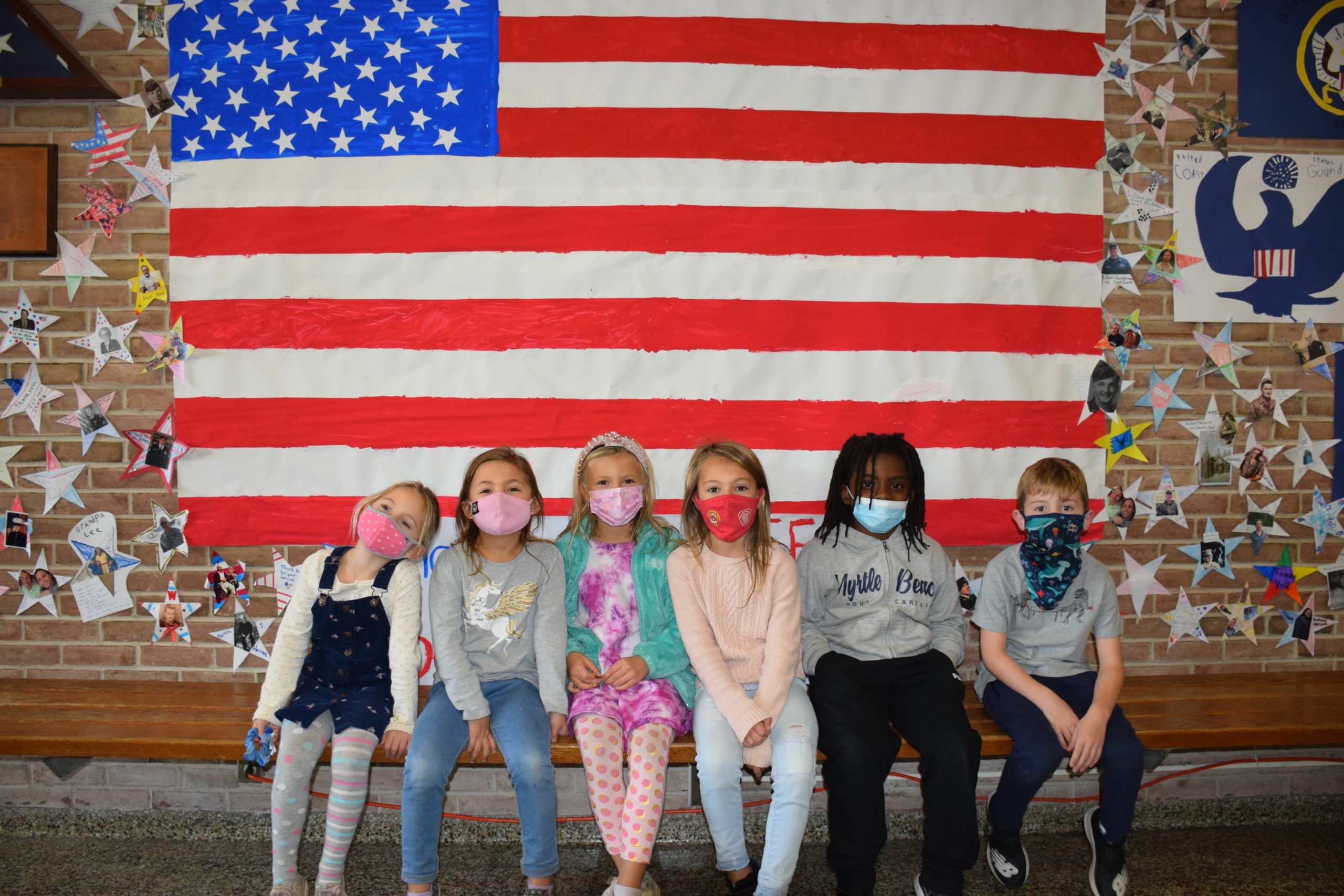 As part of a Veterans Day lesson, first grade students at Westhampton Beach Elementary School created a Hall of Heroes in the main vestibule of their school. They made colorful signs, noting the five branches of the military, and a giant paper American flag. All students in the school were then invited to contribute to the project by gluing photos of family members and friends who are veterans to paper stars that are displayed on the wall.