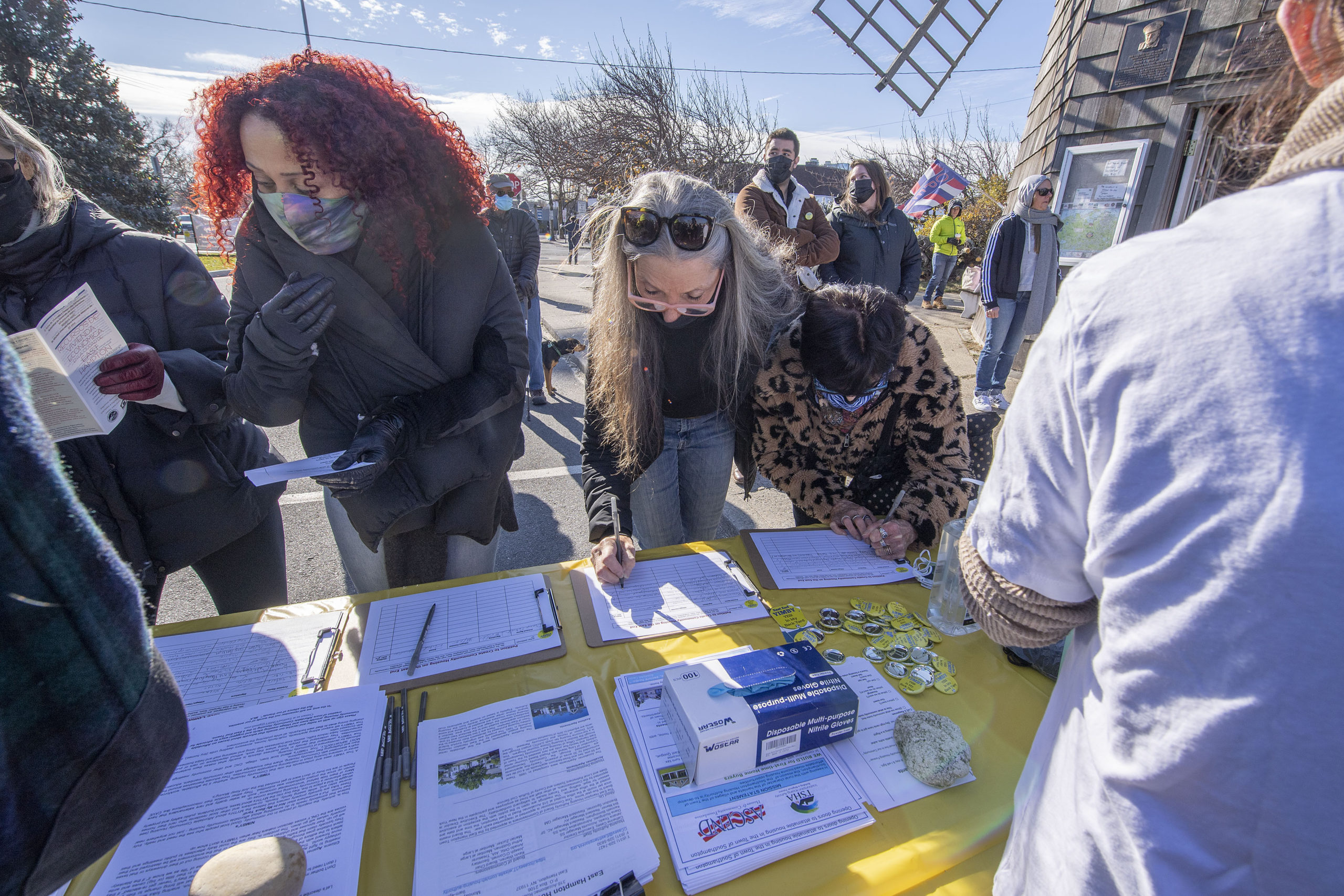 Attendees sign petitions at the East End YIMBY Rally for Affordable Housing, at the windmill on Long Wharf in Sag Harbor on Saturday.  MICHAEL HELLER