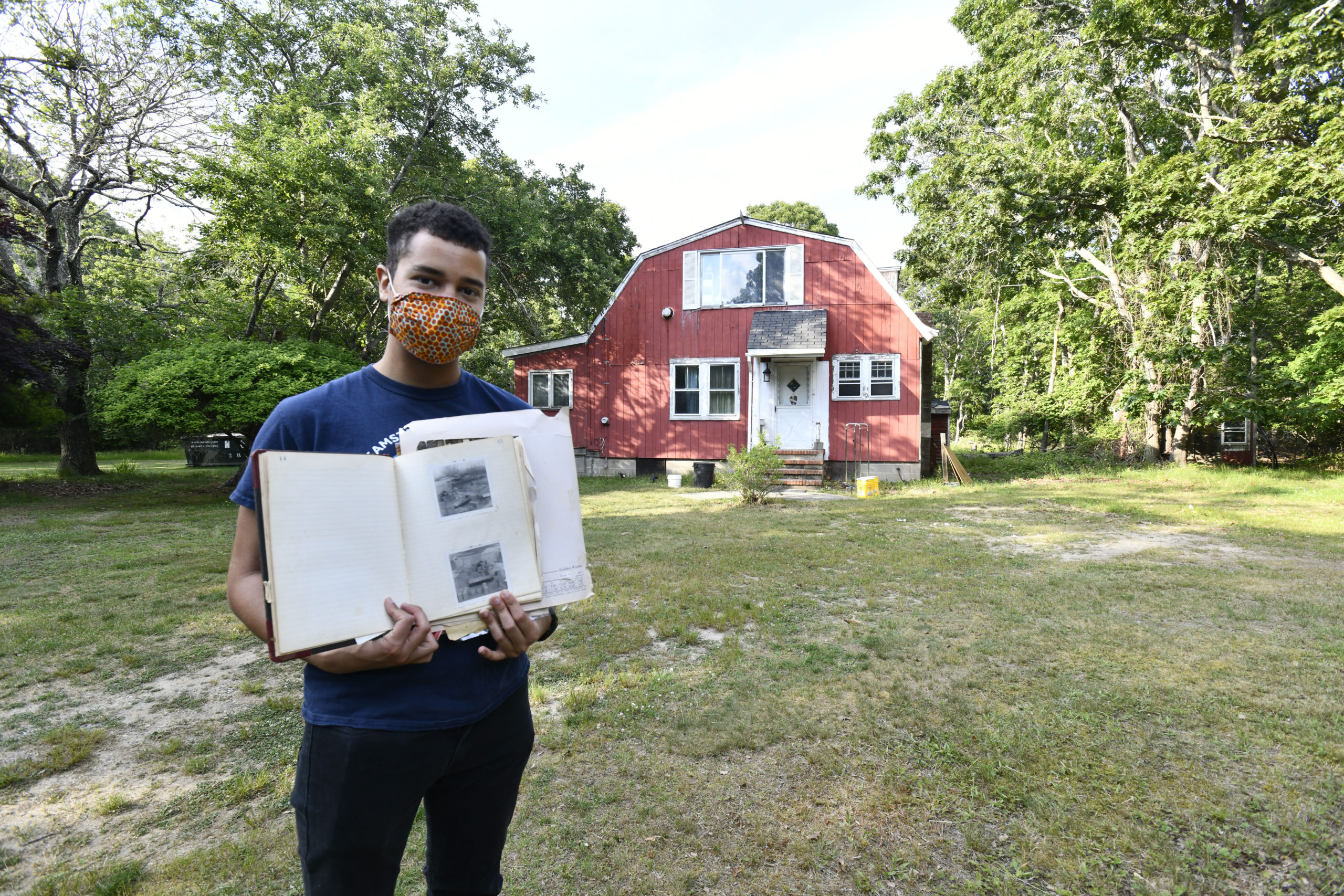 Jeremy Dennis in front of Ma's House with a family album during the 2020 renovation of the property.