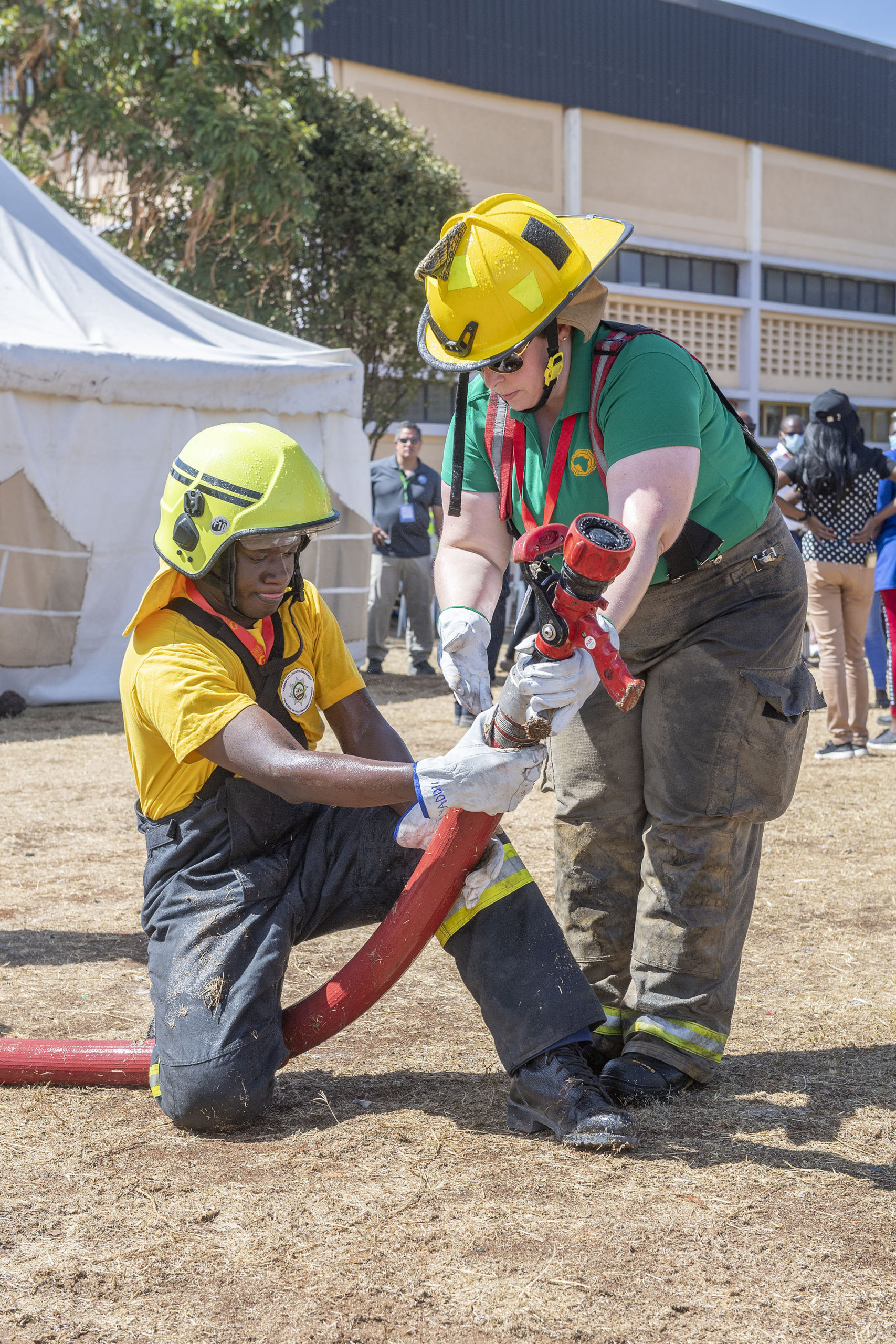 Texas firefighter and EMT Jennifer Bardwell gives advice on hose-handling techniques to a Kenyan firefighter during the Africa Fire Mission trip to Nairobi, Kenya.