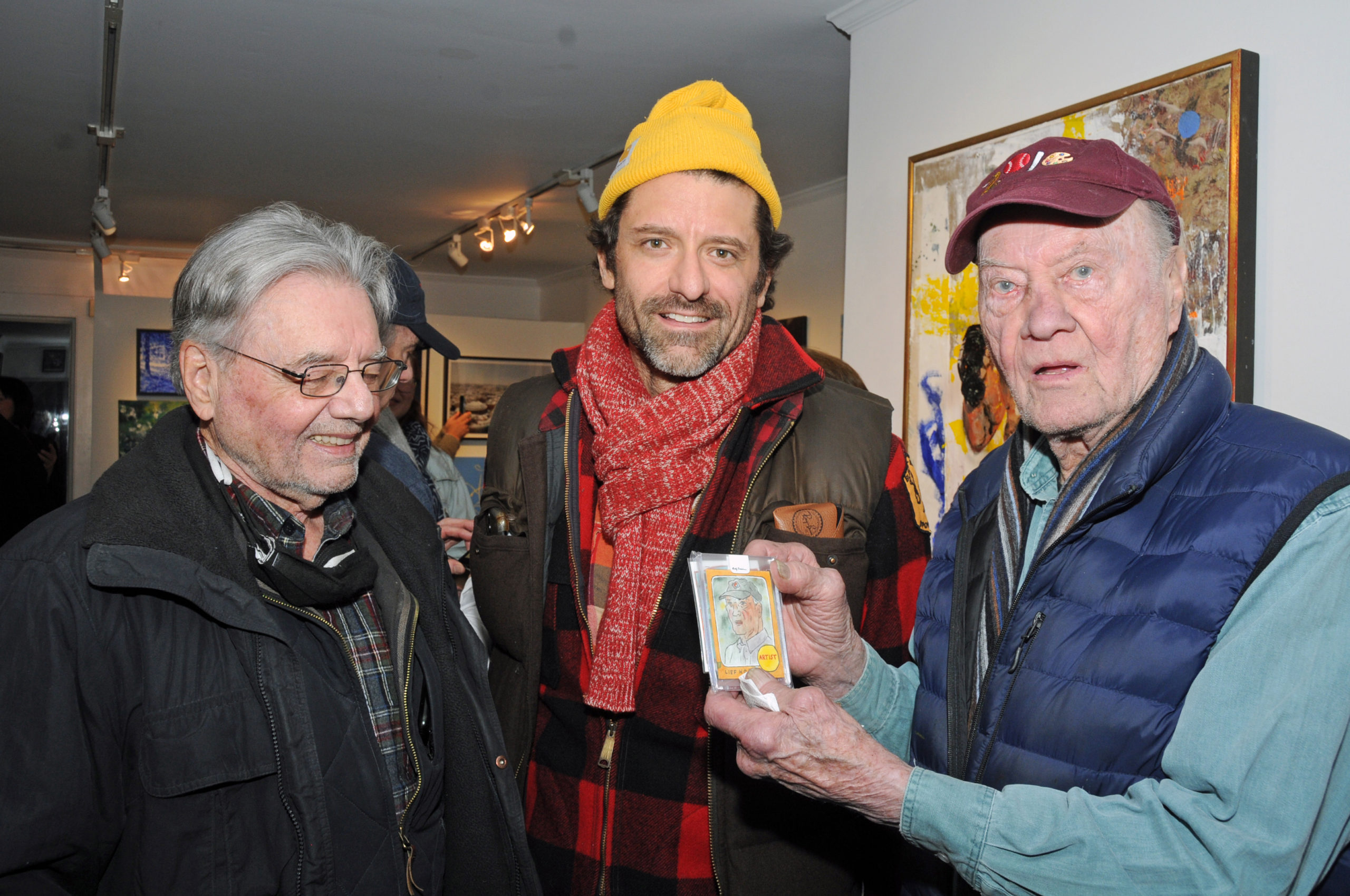 Artist Walter Bernard, Andy Friedman and Artists and Writers Game founder and artist Leif Hope with his baseball card self-portrait at Kathryn Markel Fine Arts Gallery in Bridgehampton on Saturday at the opening of the Artists & Writers Charity Softball Game's 