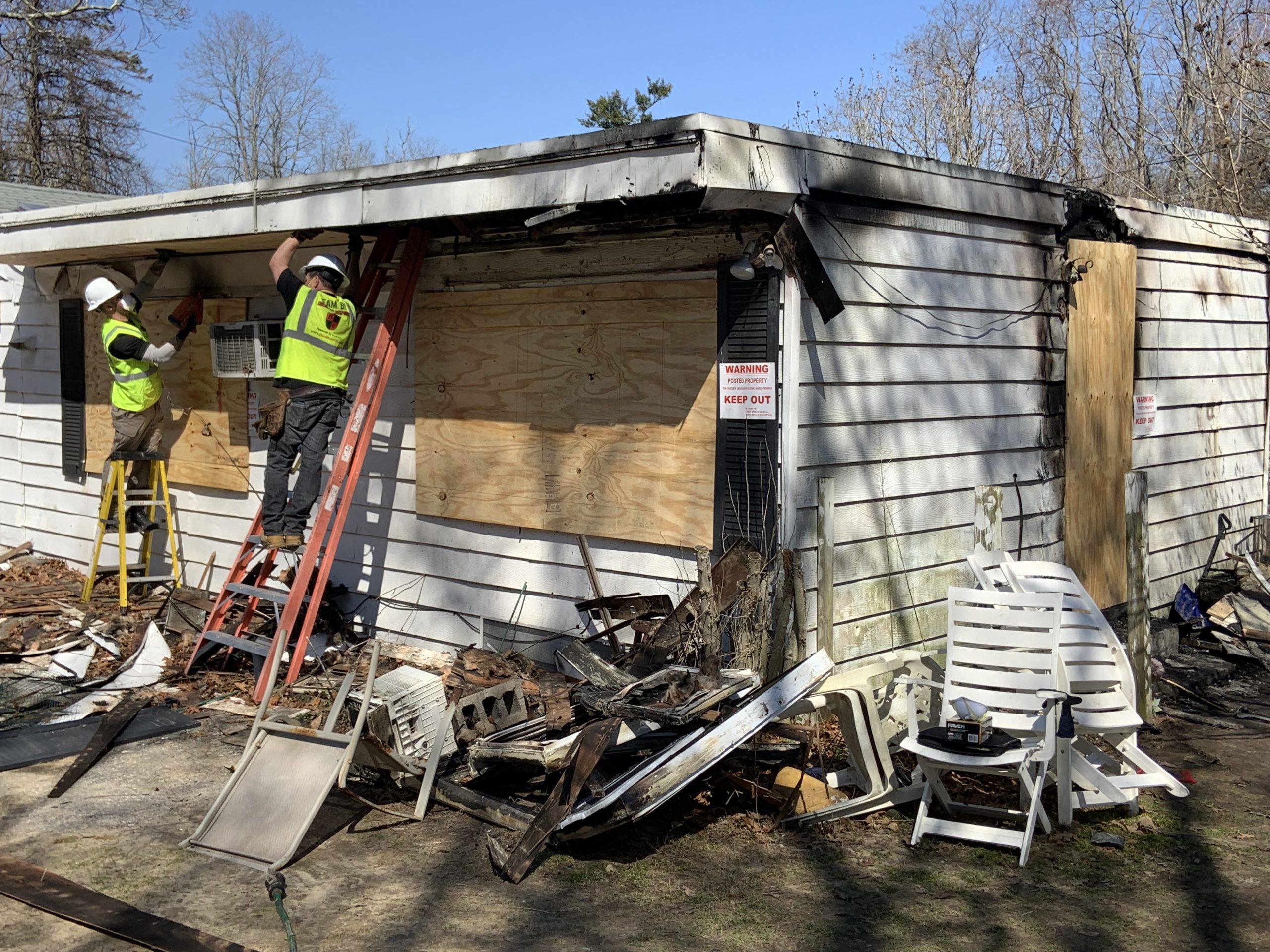 Workers with Bulovas Restorations Inc. board up a house on Narrow Lane in Bridgehampton that was gutted by fire early Friday morning. STEPHEN J. KOTZ