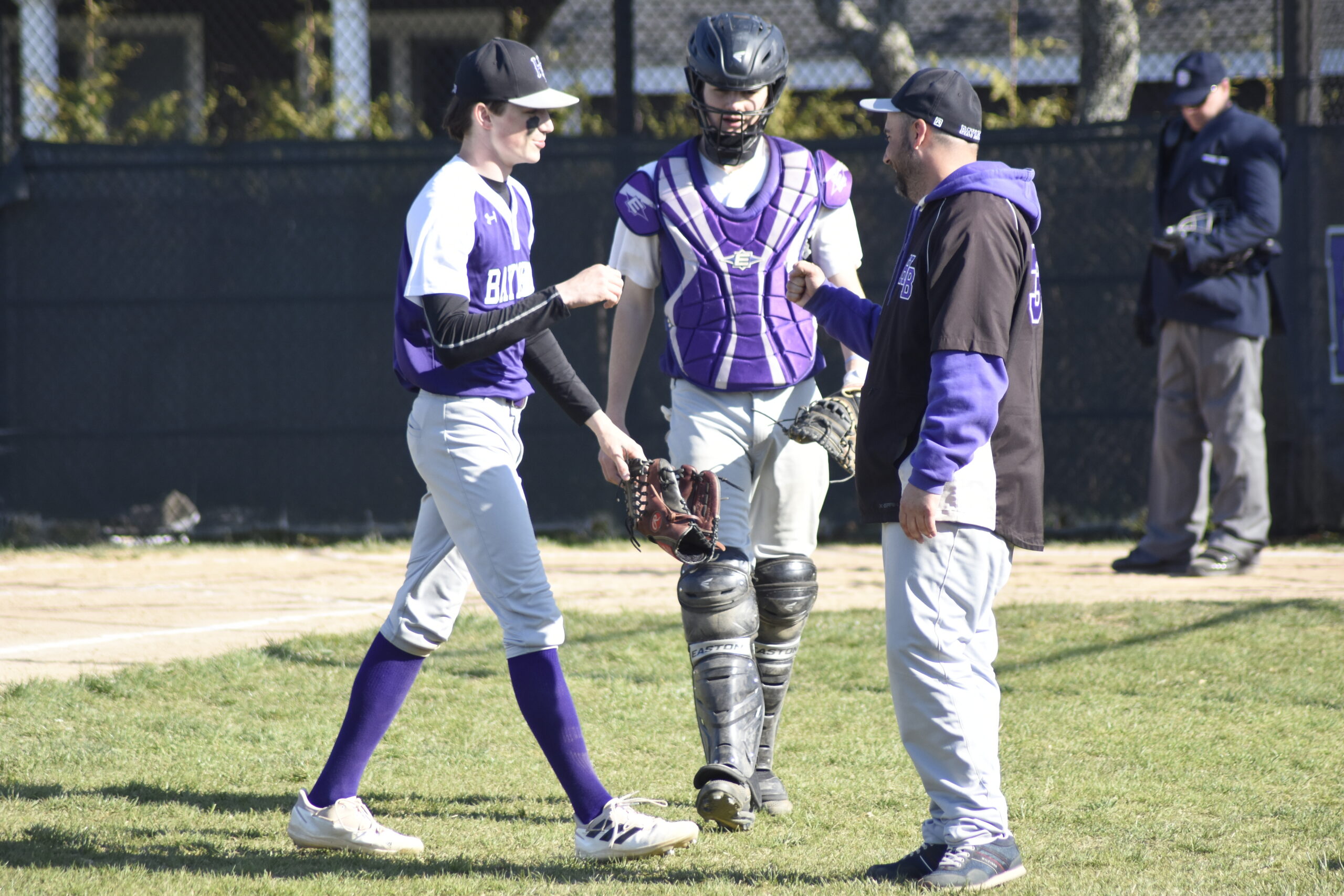 Hampton Bays starting pitcher Patrick Donahue gets congratulated by head coach Rob Pinney and catcher Aidan Kamp after recording a strikeout to get out of an inning.   DREW BUDD