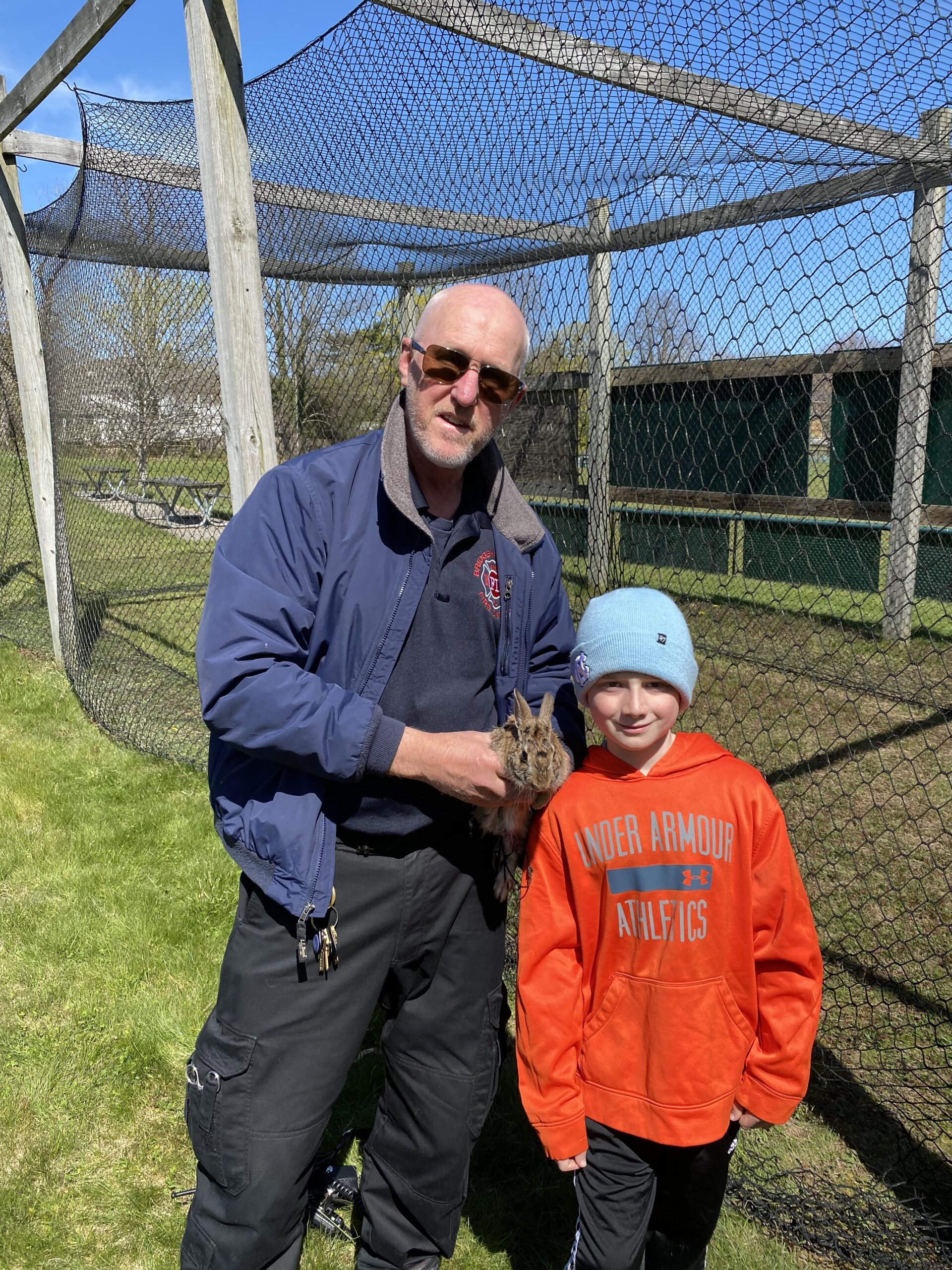 Brian Doyle with his son Brendan, a fourth-grader at Tuckahoe School who, while on his way to batting practice recently found a bunny tangled in the batting cage netting.  He ran to the Bridgehampton Fire Station and found Paul Rittenhouse, a paramedic, who assisted him in removing the exhausted bunny from the netting and returning it to his mother. COURTESY BRIAN DOYLE
