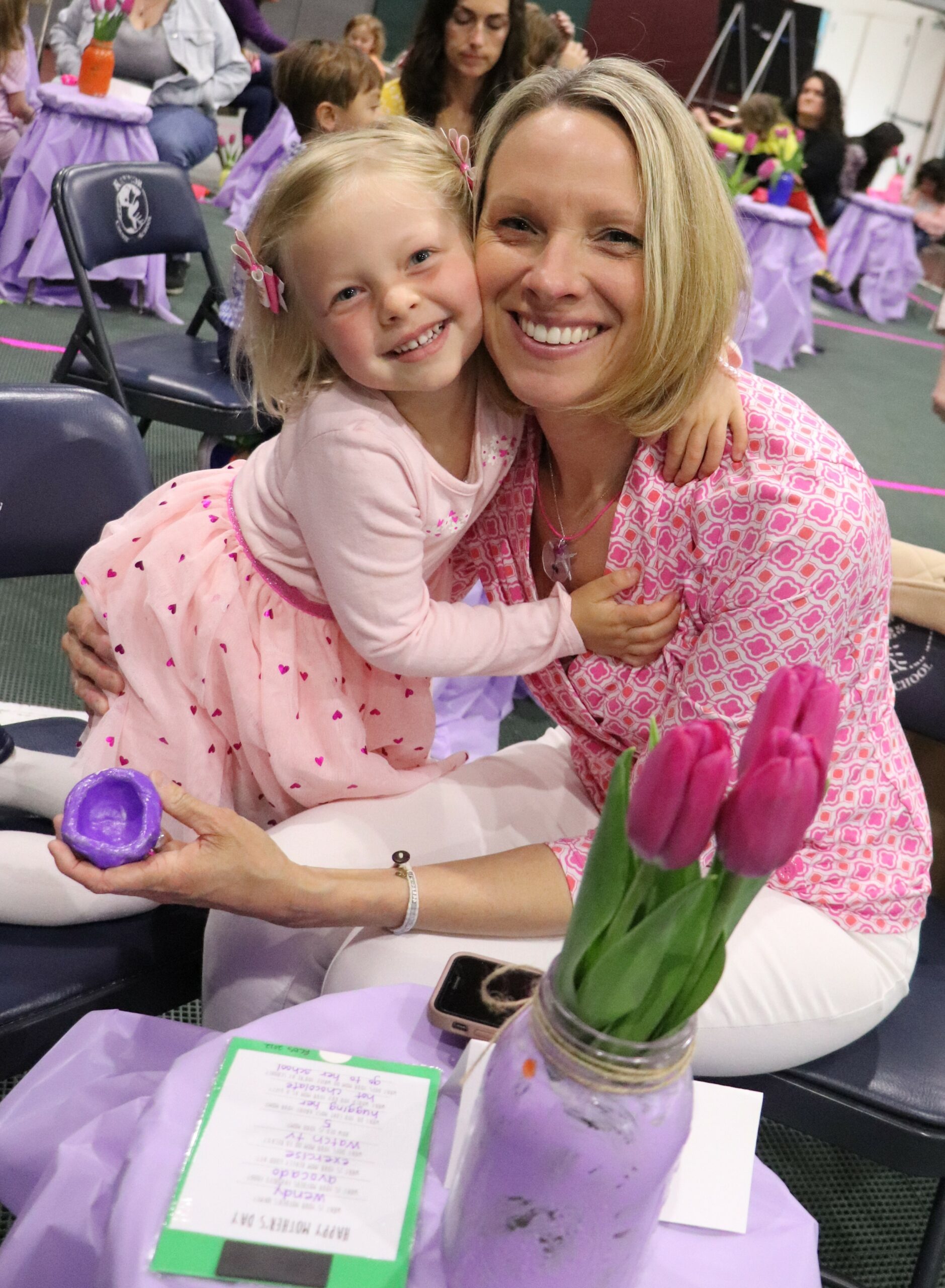 On Friday, May 6, the pre-Kindergarten students at Raynor County Day School  hosted a Mother's Day Tea Party for their mothers.   During their visit, the ladies were treated to a musical performance, tea, and tasty treats.  In addition, the children created handmade gifts for their mothers which included pinch pots, floral vases, handcrafted necklaces, and gift certificates to be redeemed for services such as putting away toys or washing the dishes.  Charlotte Turbush cuddles with her mother, Wendy Turbush, at the event. COURTESY RAYNOR COUNTRY DAY SCHOOL