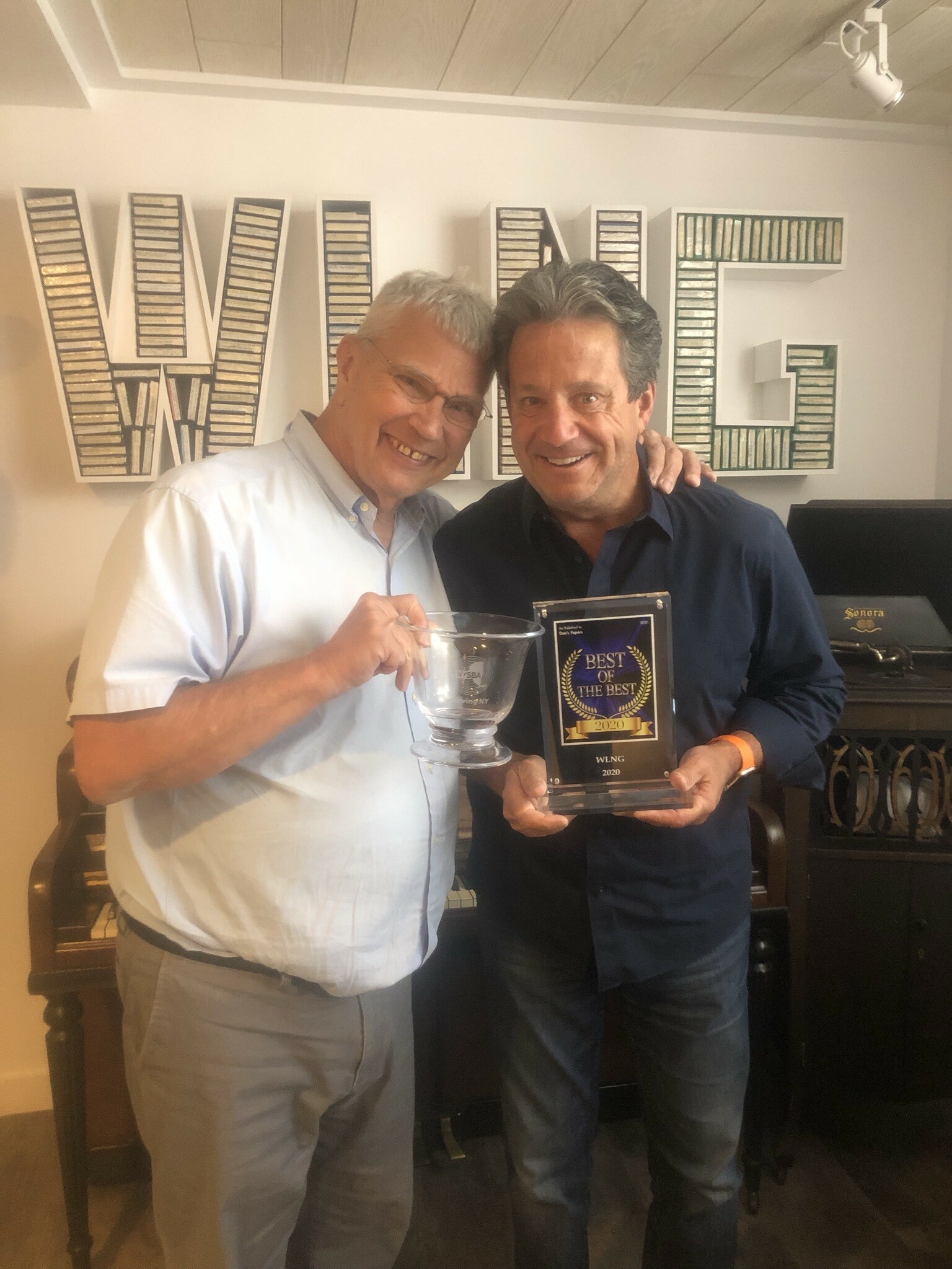 WLNG 92.1 FM deejay and general manager Gary Sapiane with Bill Evans, the station's owner, and a couple of their awards. COURTESY WLNG RADIO