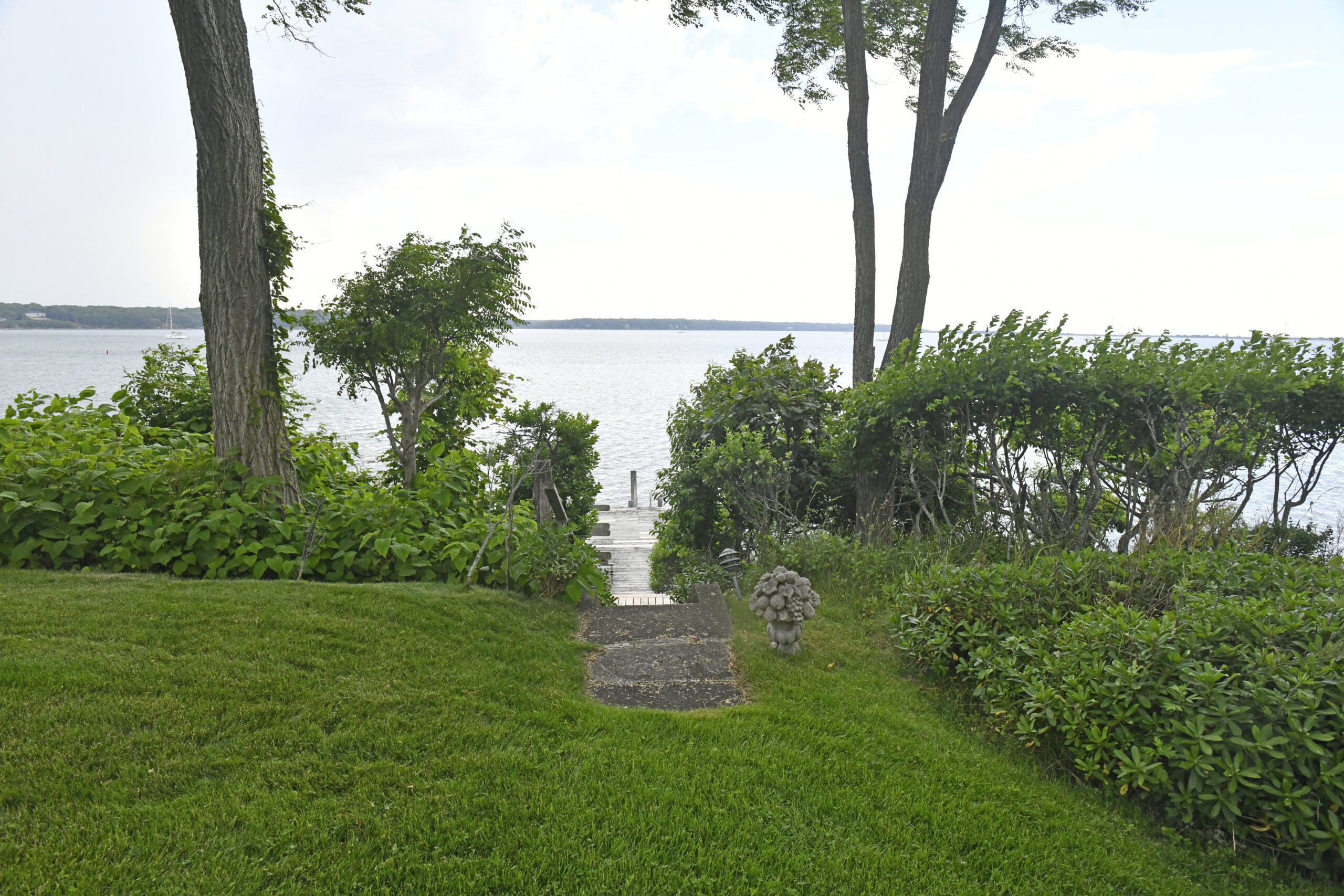 Ms. Landey's property is lushly landscaped with hidden nooks where Thunderhead black pines accentuate fanning ferns. Steep concrete steps lead to the dock.   DANA SHAW