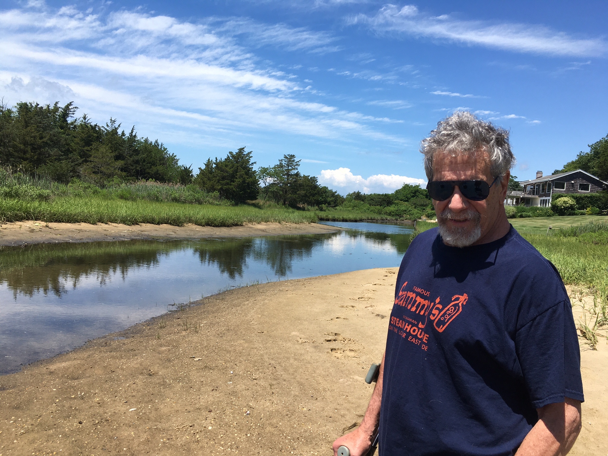 Cliff drive resident Van Brody stands on the large spit of sand that was once water in a navigable canal in  the Bay Point section of Sag Harbor.    KITTY MERRILL