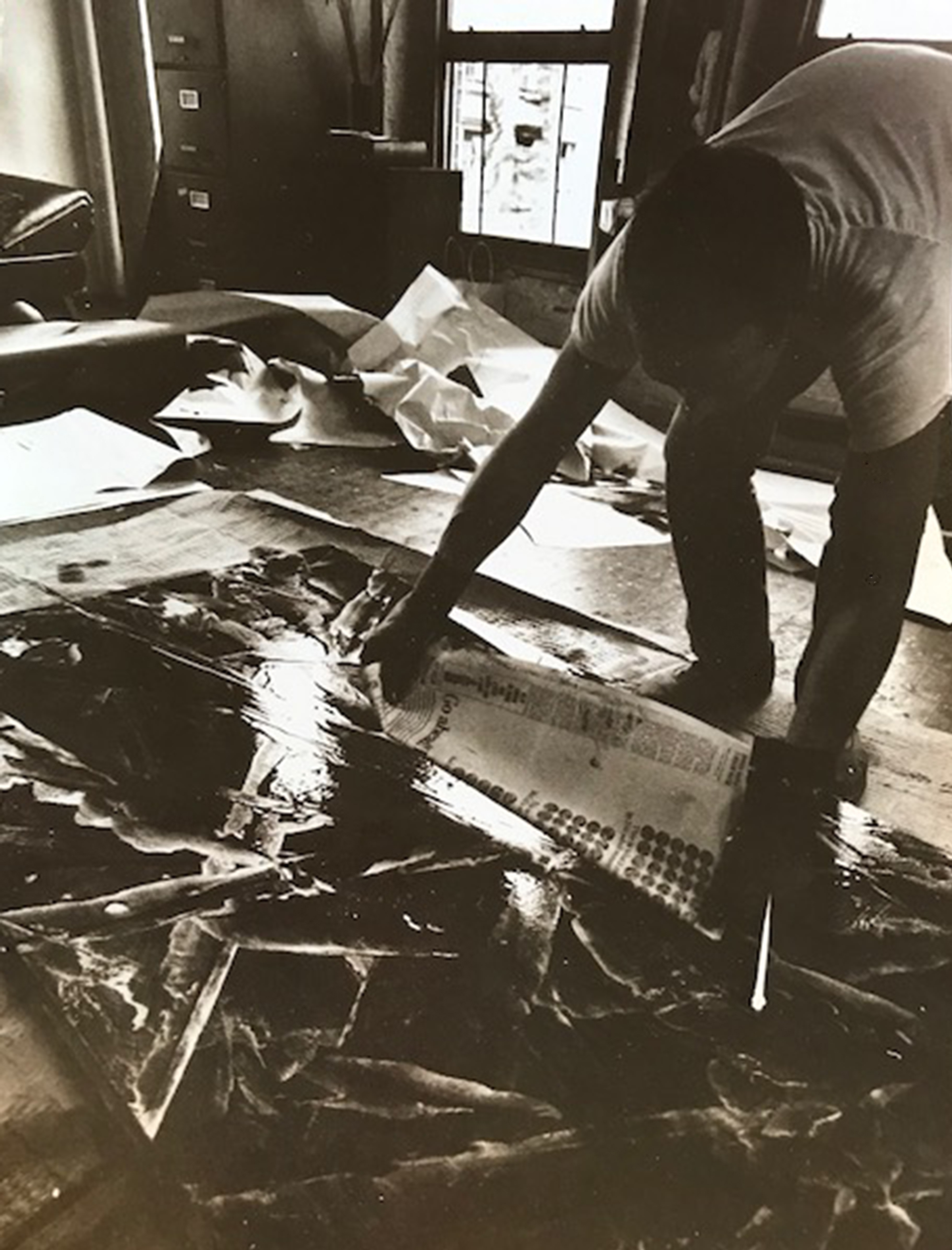 Terence Netter blotting a canvas with newsprint to create abstract textures, 1970s.