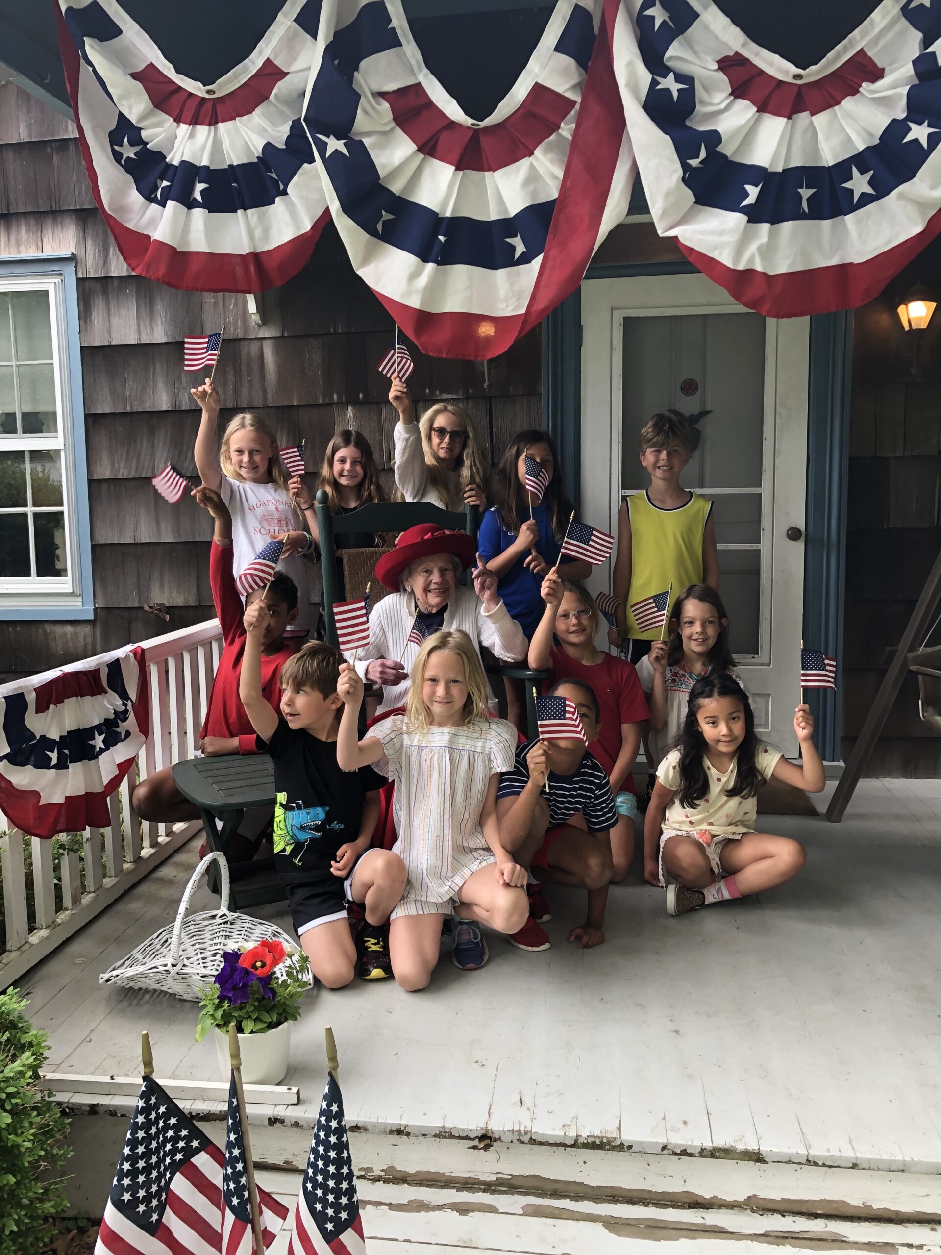 Students from the Sagaponack School gathered, as they do every year, on the porch of Barbara Albright, a longtime resident of Sagaponack and the school's best cheerleader, to sing patriotic songs an recite the pledge of allegiance for Flag Day. Albright's house is one of the oldest homes in Sagaponack; it was built in the 1700s. COURTESY SAGAPONACK SCHOOL