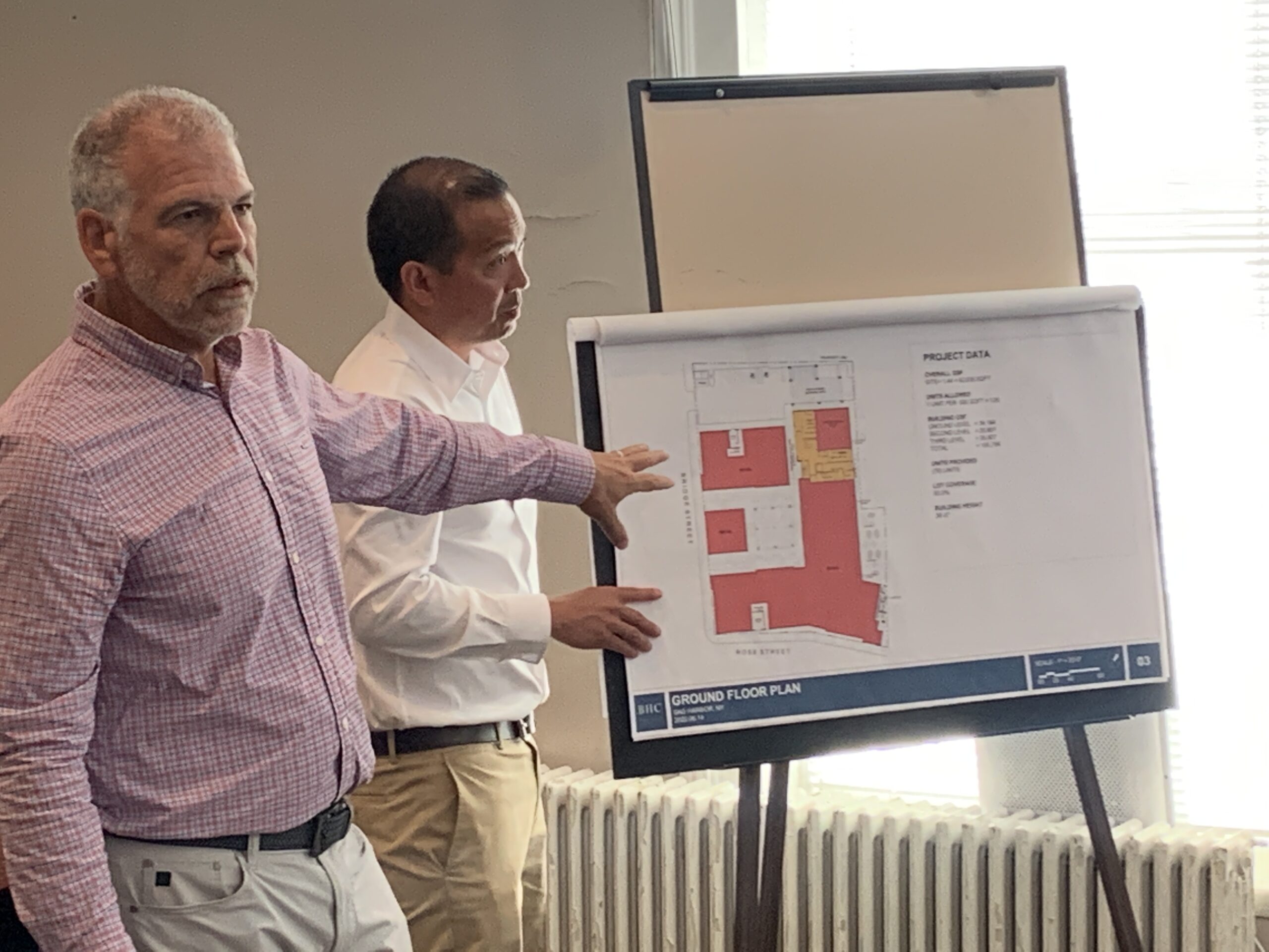 Salvatore Coco, left, of BHC Architects, and Roger Pine of Conifer Realty, show plans for the affordable housing development proposed by Adam Potter for property off Rose and Bridge streets to members of the Sag Harbor Village Board on Friday. STEPHEN J. KOTZ