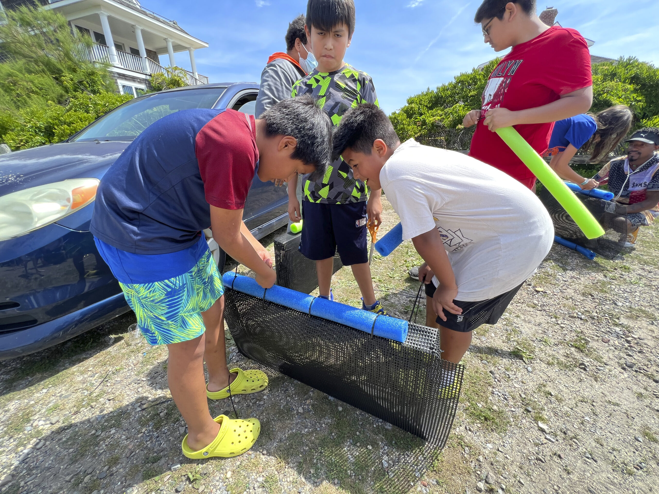 Kids from the Bridgehampton Child Care and Center constrict an oyster cage at the Moriches Bay Project's learn how to make an oyster cage and set up a farm event in Westhampton on July 8.  DANA SHAW