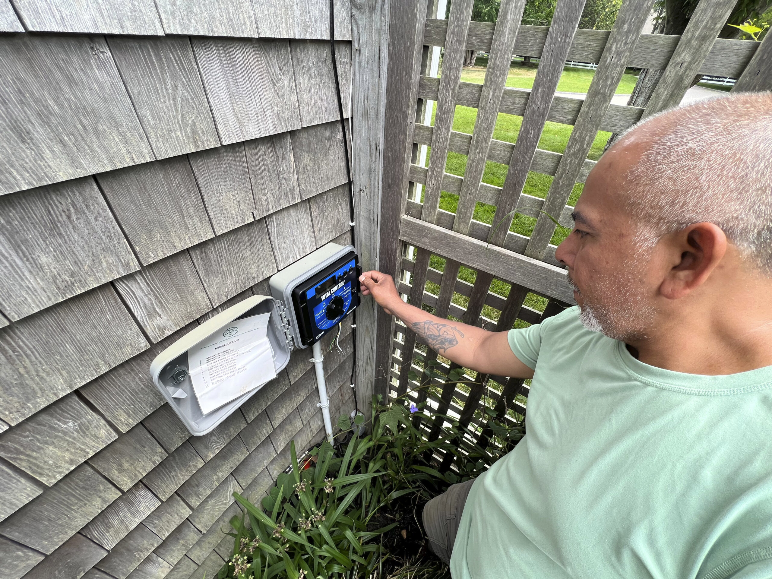 Hilario Alvarez of James H. Lynch, Inc. sets the timer on a sprinkler system.  DANA SHAW