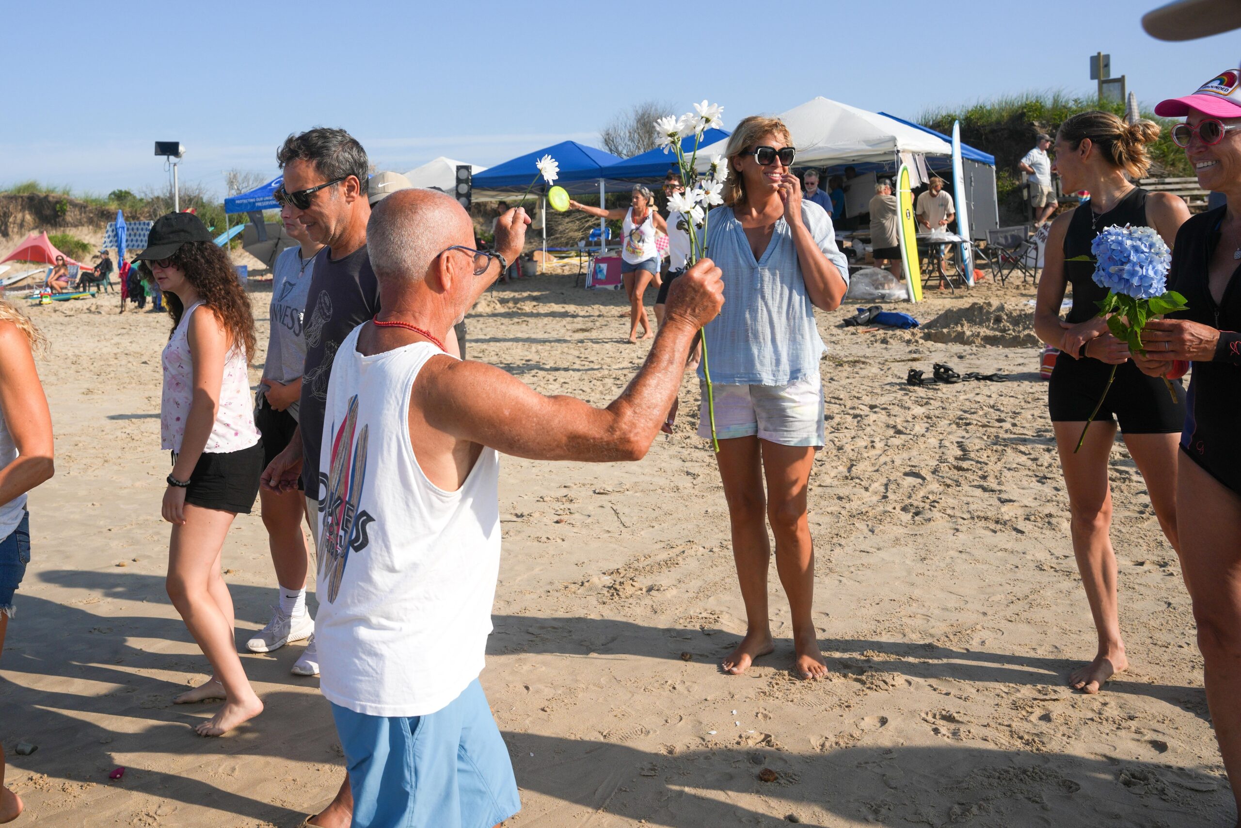 Roger Feit hands out flowers for the memorial prior to the 24th annual Rell Sunn Memorial Surf Contest at Ditch Plains on Saturday morning.    RON ESPOSITO