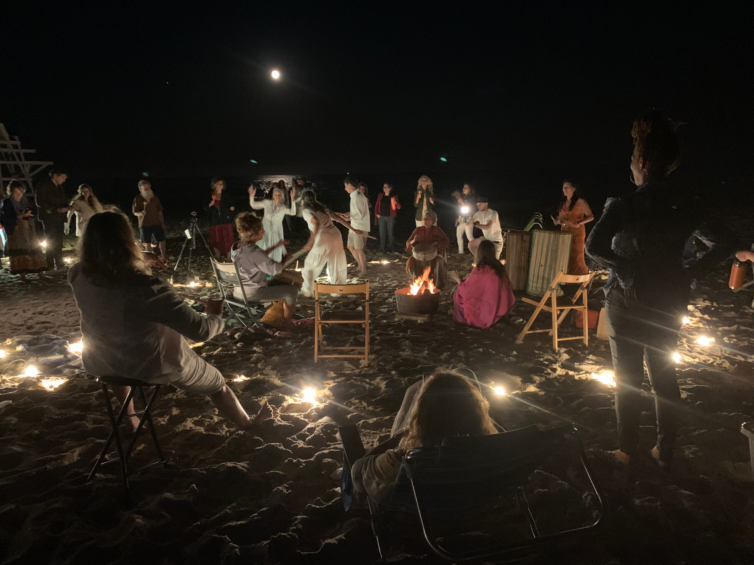 Artist Christina Sun, standing at right with drum, responds to a love letter from West Coast artist Catherine Scott with a piece offered on East Hampton's Main Beach under the full moon of September 10. ANNETTE HINKLE