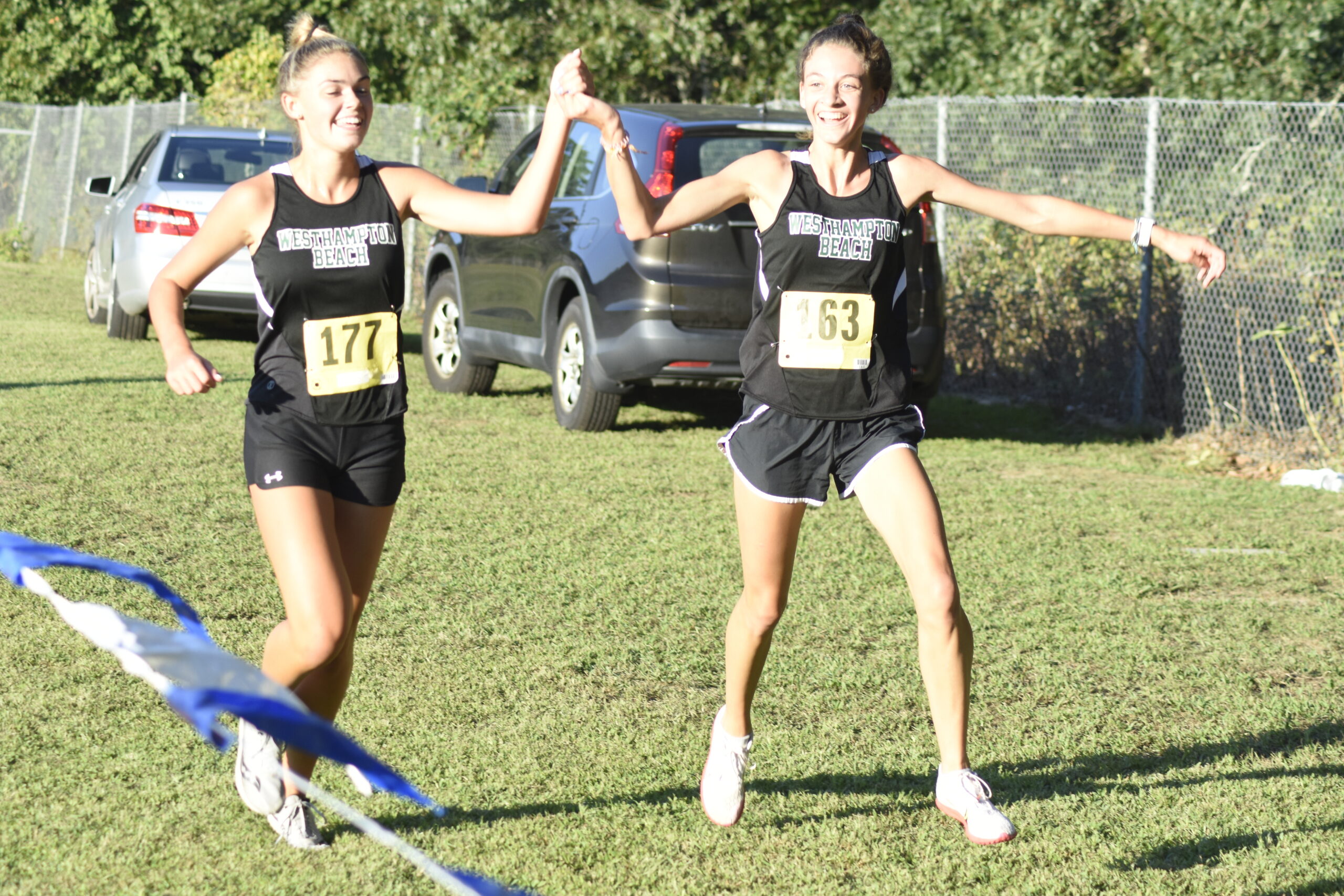 Hurricanes Jamie Kelly and Gabby Wendel cross the finish line together at the Peconic Invitational.    DREW BUDD