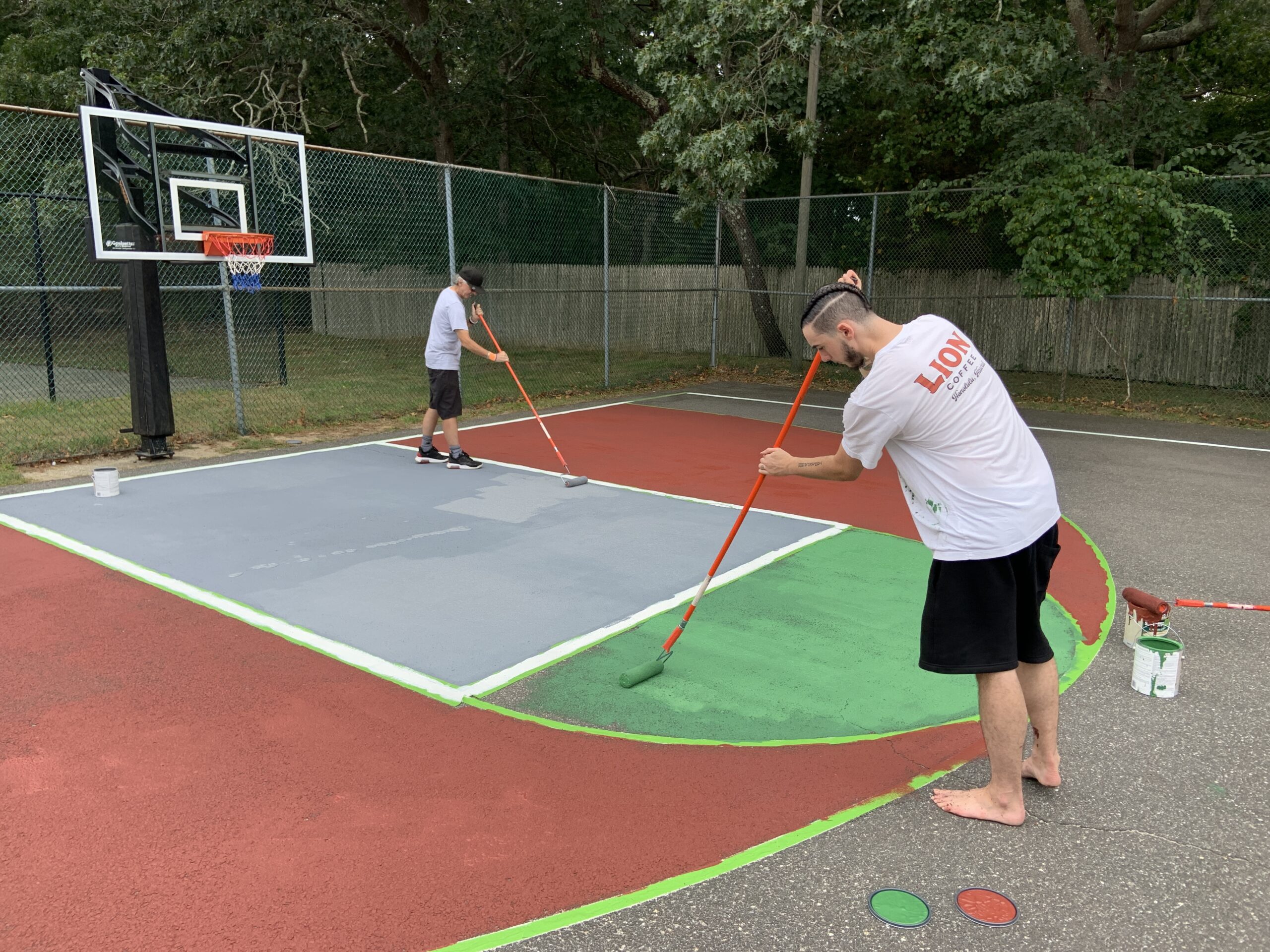 Robert Durkin, left, and his son Adrian paint one end of the Bridgehampton Child Care and Recreational Center's basketball court on Sunday. STEPHEN J. KOTZ