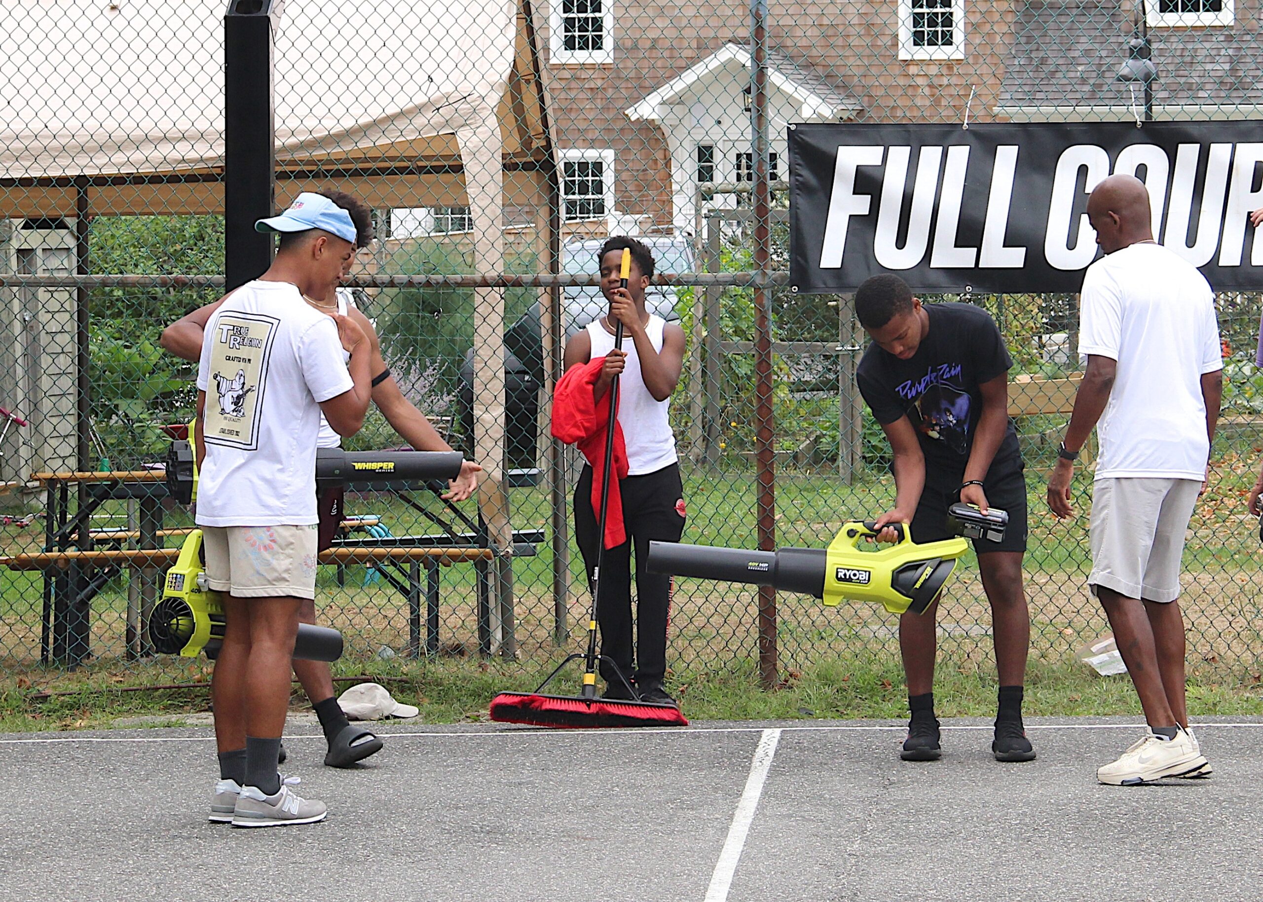 Current Bridgehampton Killer Bee basketball players and former head coach Carl Johnson help out with the makeover of the court.    KYRIL BROMLEY