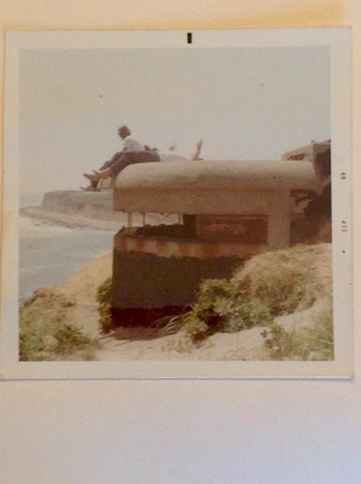 A view of the pillbox in 1969 with visitor sitting atop its roof looking out at the Atlantic.