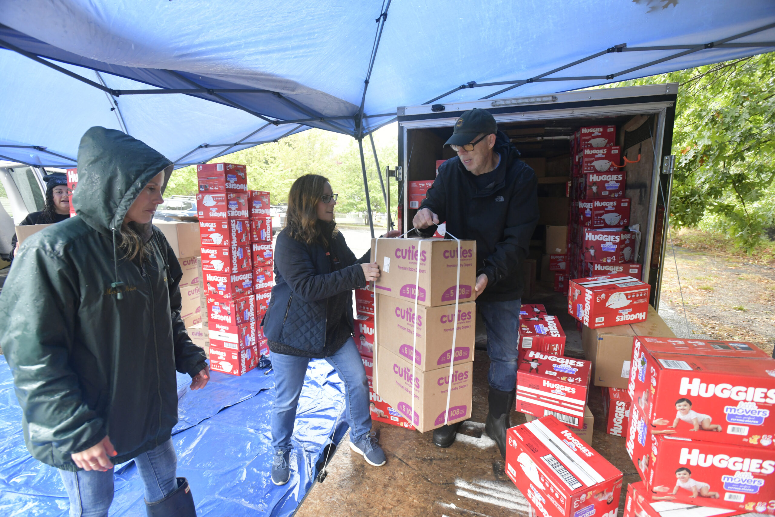 Marit Molin,  Heather Edwards and Chuck MacWhinnie distribute diapers on a rainy Saturday in the parking lot at the Unitarian Universalist Church in Bridgehampton.  DANA SHAW