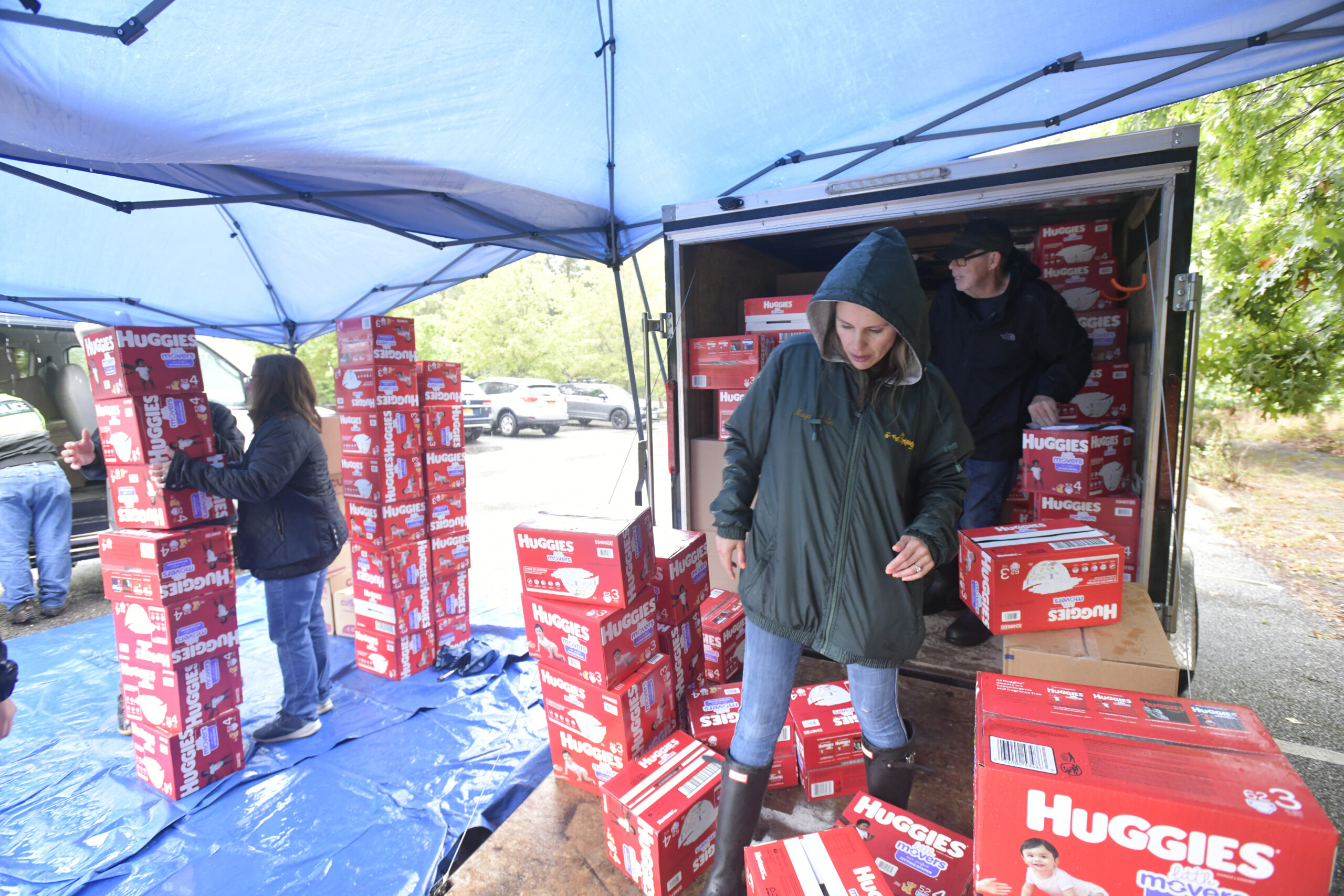 Heather Edwards, Marit Molin and Chuck MacWhinnie distribute diapers on a rainy Saturday in the parking lot at the Unitarian Universalist Church in Bridgehampton.  DANA SHAW