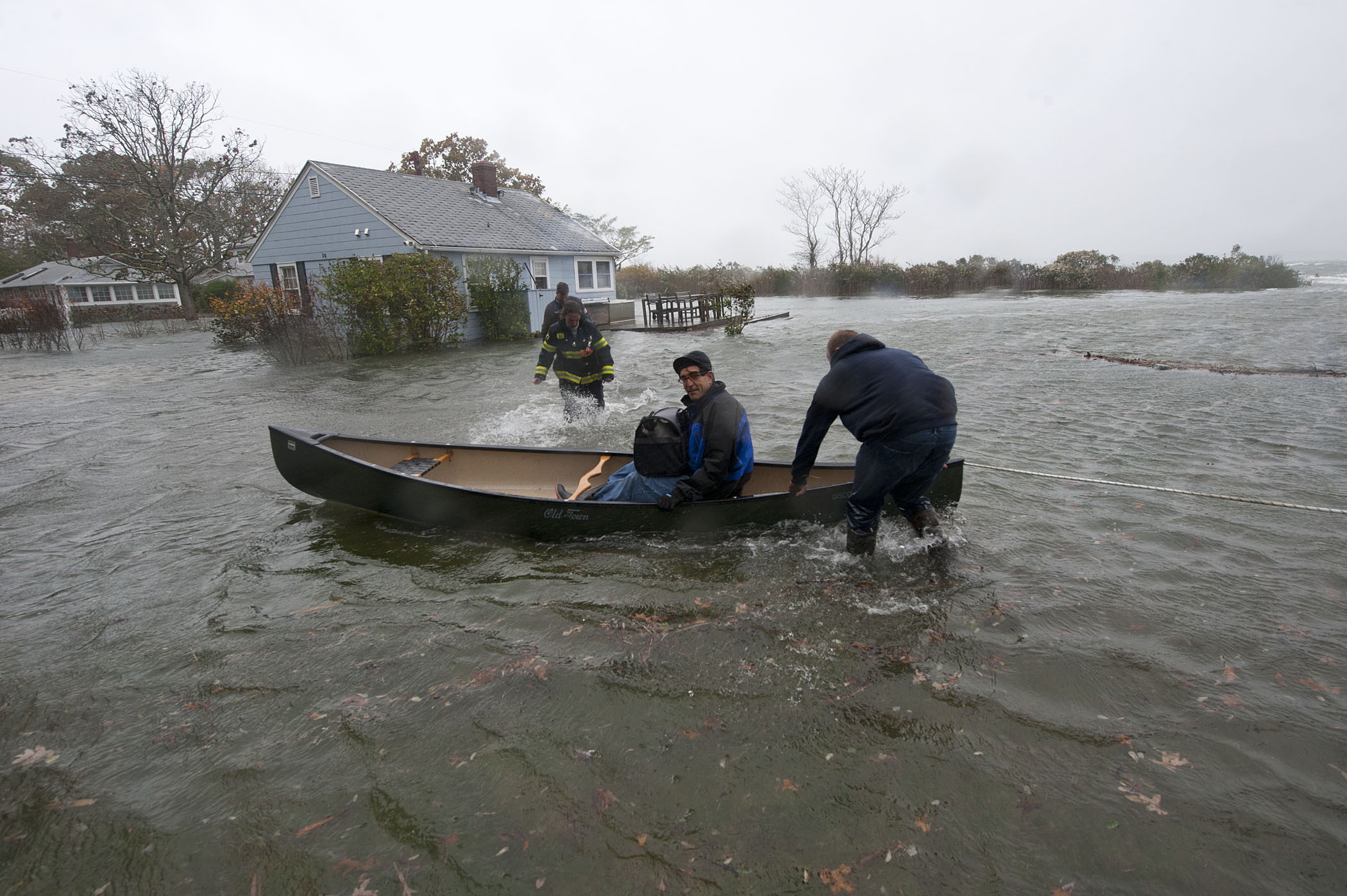 At roughly 11:00 a.m., Sag Harbor Firefighters Peter Topping, Mike Labrozzi and Kelly Bailey used a canoe to transport a Bay Avenue, Pine Neck resident and his pets who had become stranded due to rising water during hurricane Sandy on Monday, October 29, 2012.   MICHAEL HELLER