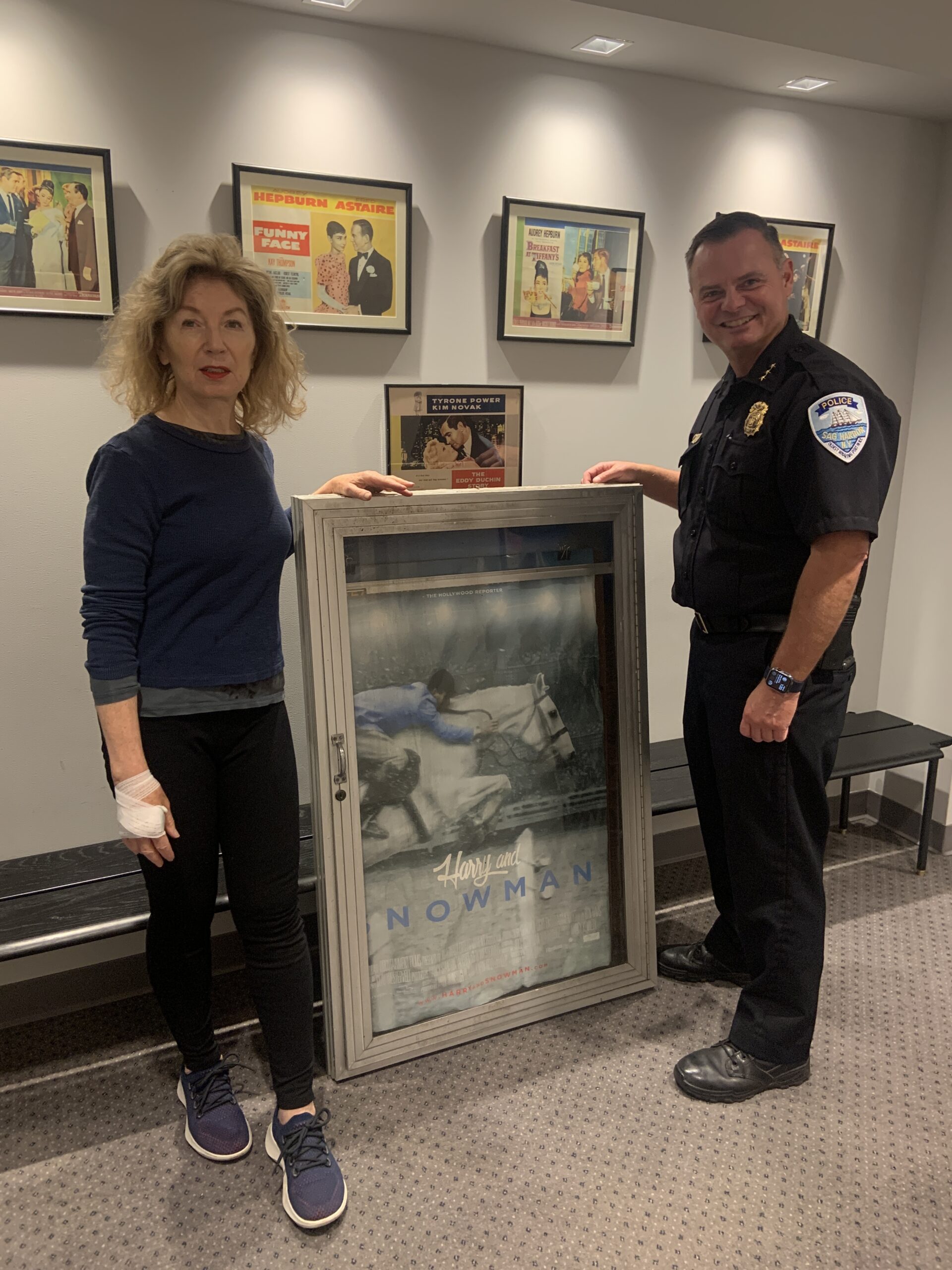 April Gornik of the Sag Harbor Cinema and Sag Harbor Village Police Chief Austin J. McGuire with a poster and display case rescued when the movie theater burned in December 2016. STEPHEN J. KOTZ