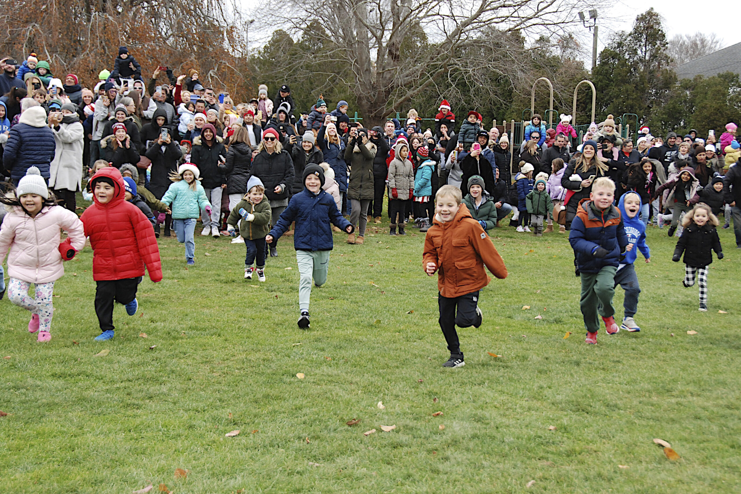 Kids rush toward Santa in Herrick Park in East Hampton on Saturday afternoon after he arrives via a Suffolk County Police helicopter.  KYRIL BROMLEY