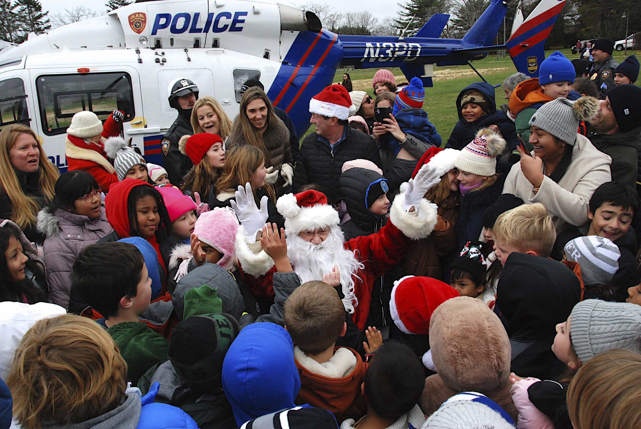 Santa is swarmed by young fans on Saturday in Herrick Park in East Hampton on Saturday afternoon after arriving via a Suffolk County Police helicopter.  KYRIL BROMLEY