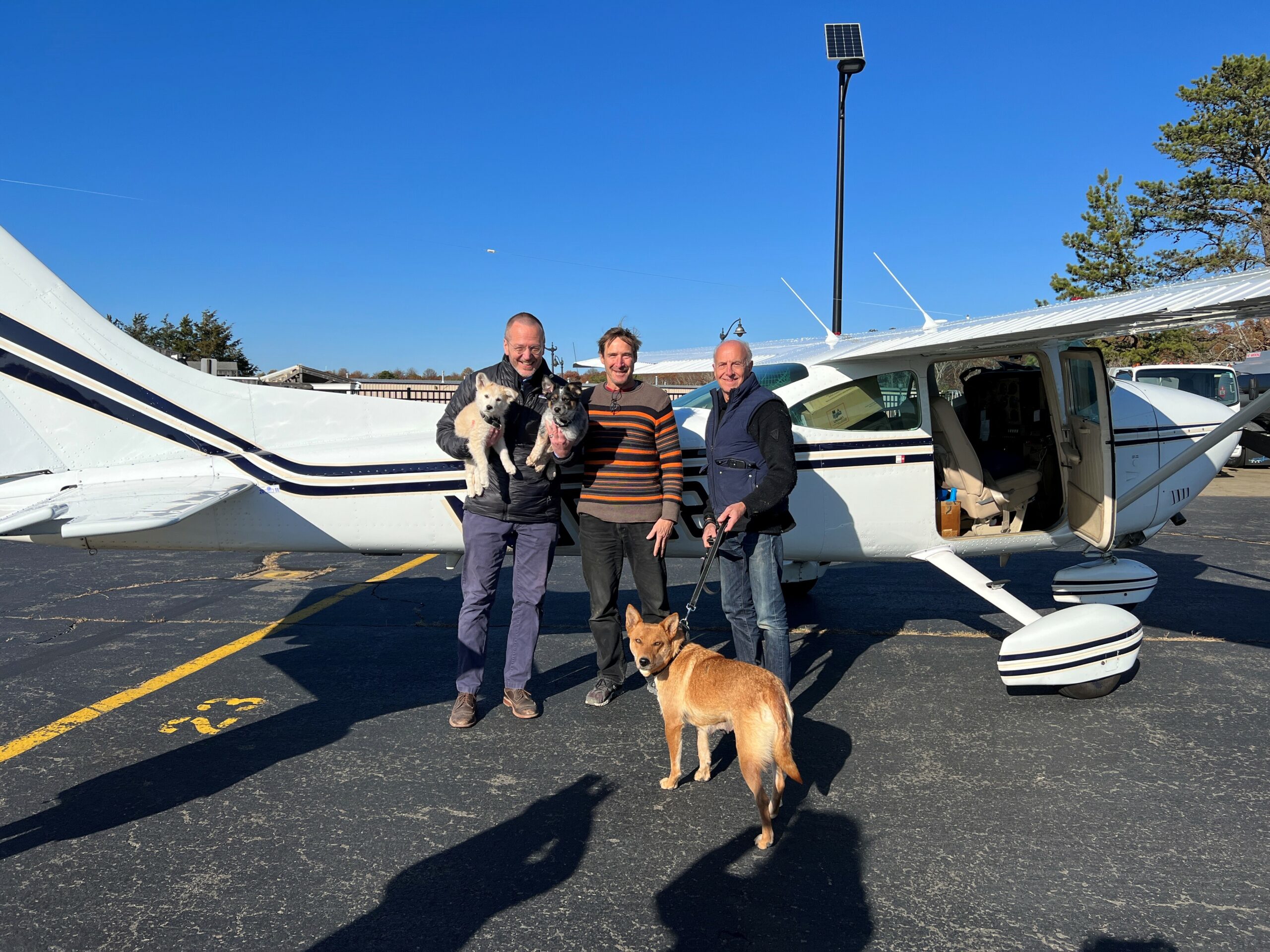 Animal Rescue Fund of the Hamptons Executive Director Scott Howe holds Biscochito and Blue Corn after pilots Dr. George Dempsey, middle, and David Reinbach, with mom Zia on leash, arrived from New Mexico. LAUREN DEMPSEY