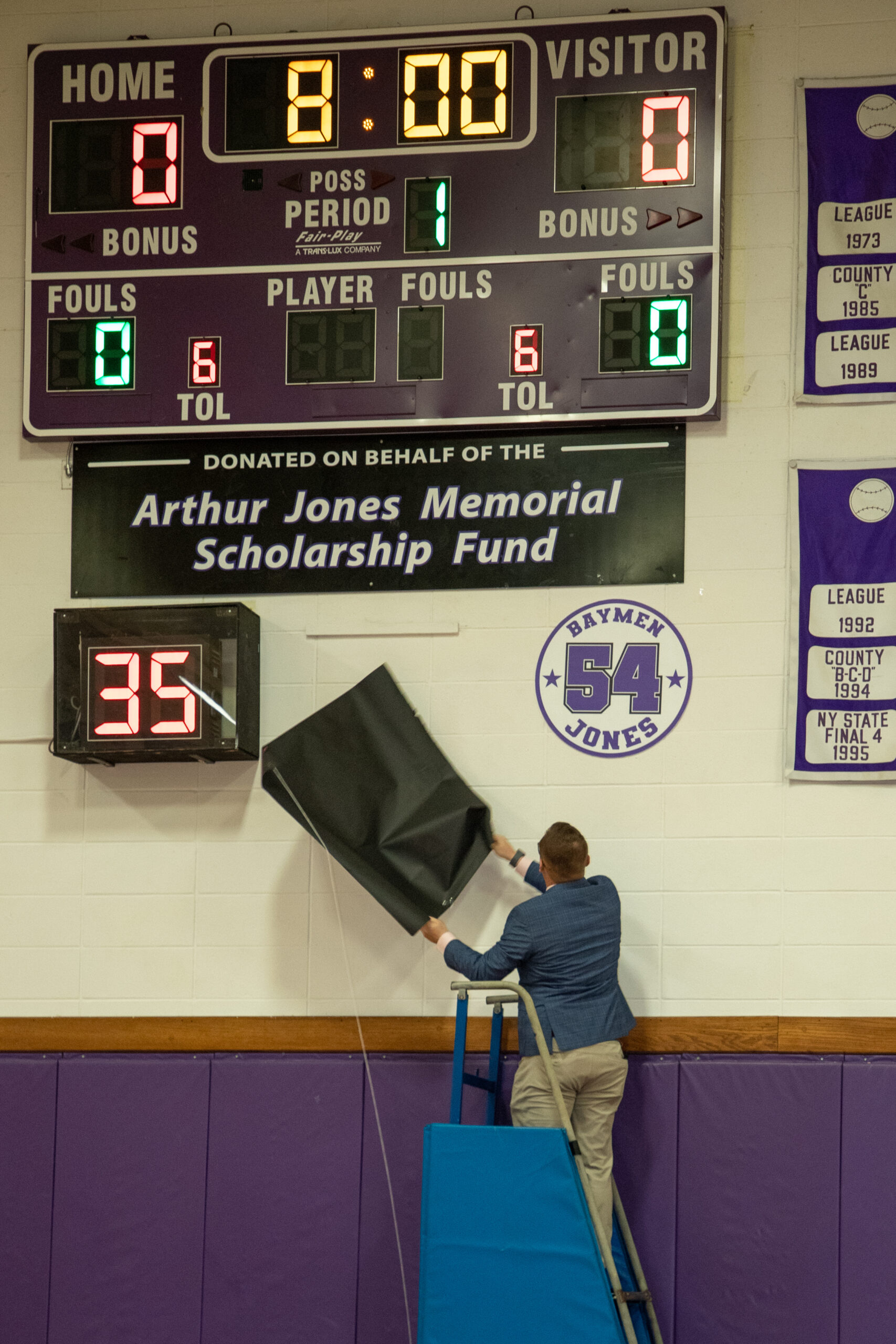 Hampton Bays Athletic Director John Foster unveils Arthur Jones's number that will sit underneath the scoreboard already in his name.     MICHAEL O'CONNOR