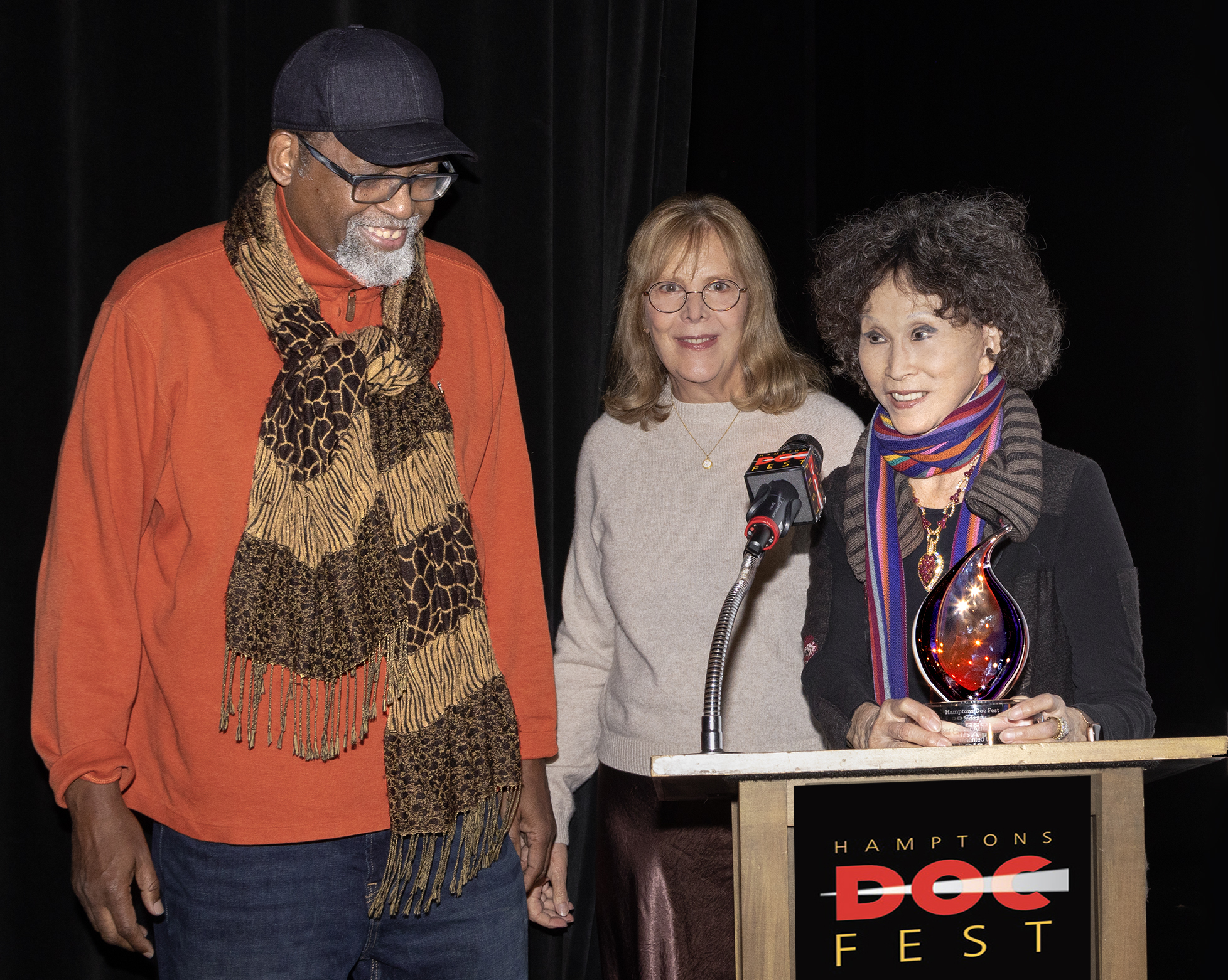 Sam Pollard receives the HDF 2022 Pennebaker Career Achievement Award at the December 3 gala at Bay Street Theater from filmmakers Chris Hegedus, who was Pennebaker’s partner, and Lana Jokel, who sponsors the annual award. CB GRUBB/COURTESY HAMPTONS DOC FEST