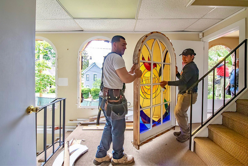 Workers remove a stained glass window. MICHAEL HELLER PHOTO