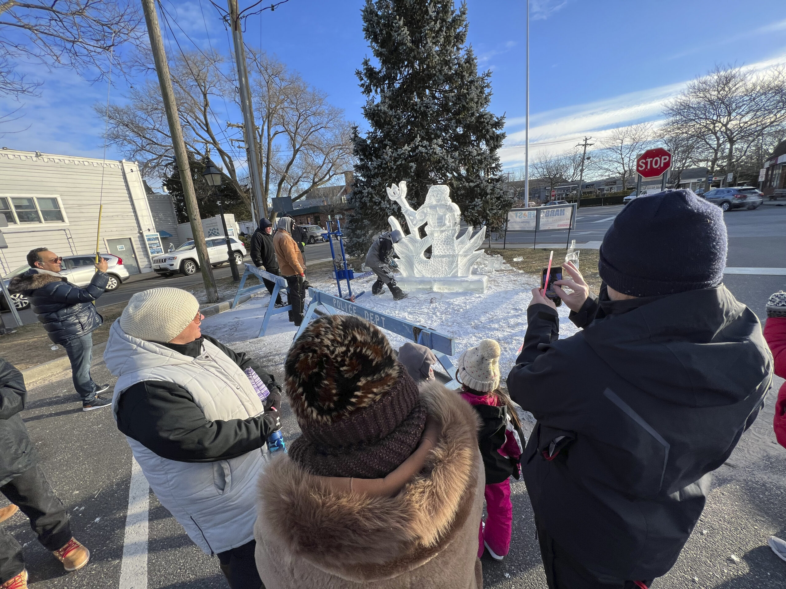 The crowd watches as ice carver Rich Daly works on a sculpture of Neptune on Long Wharf on Saturday during HarborFrost.   DANA SHAW